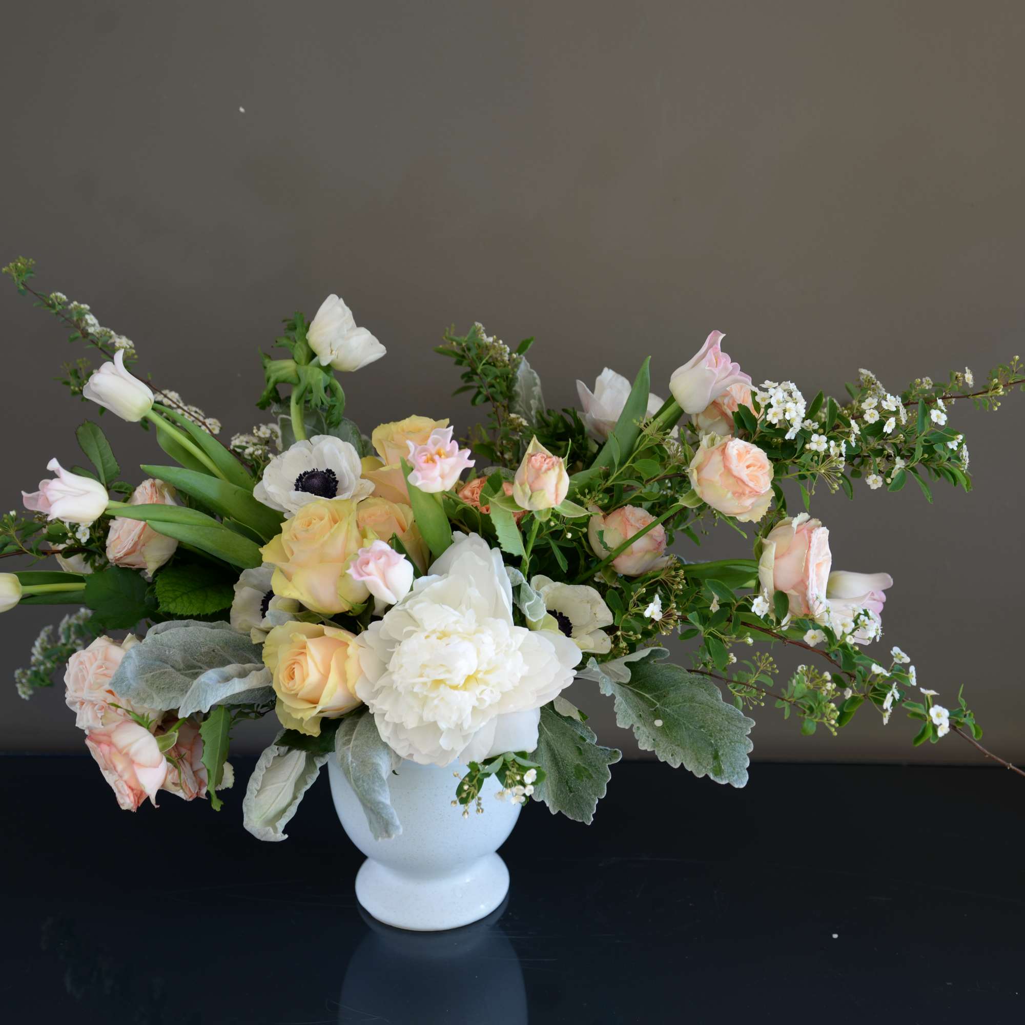 Pastel floral arrangement in a white vase with roses and tulips