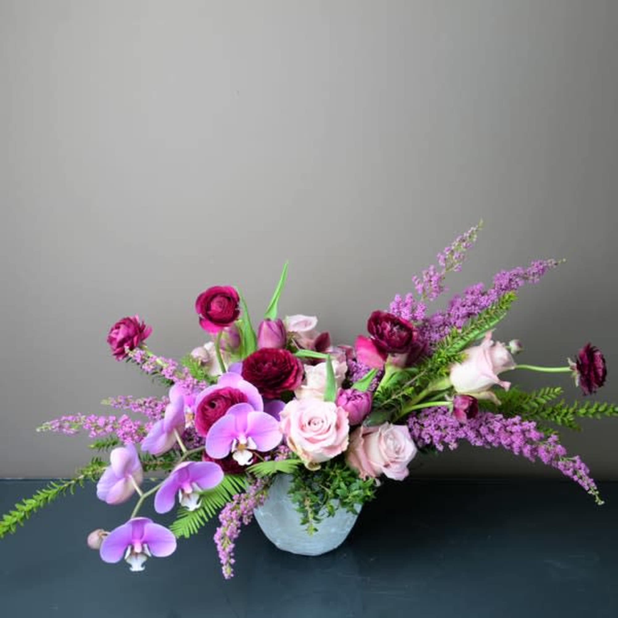 Pink and purple floral arrangement in a white vase