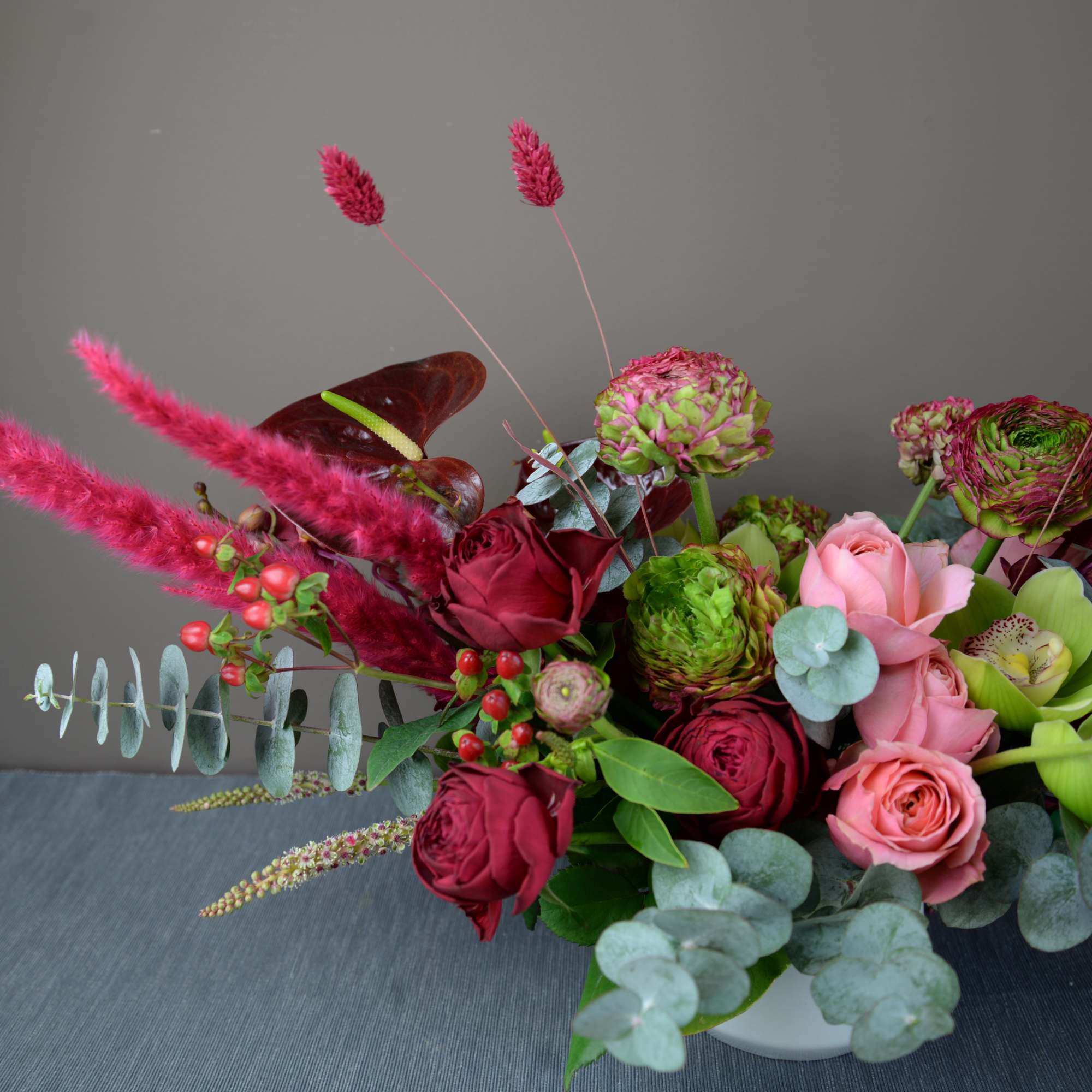 Bouquet of pink and burgundy roses with green blooms in a white vase