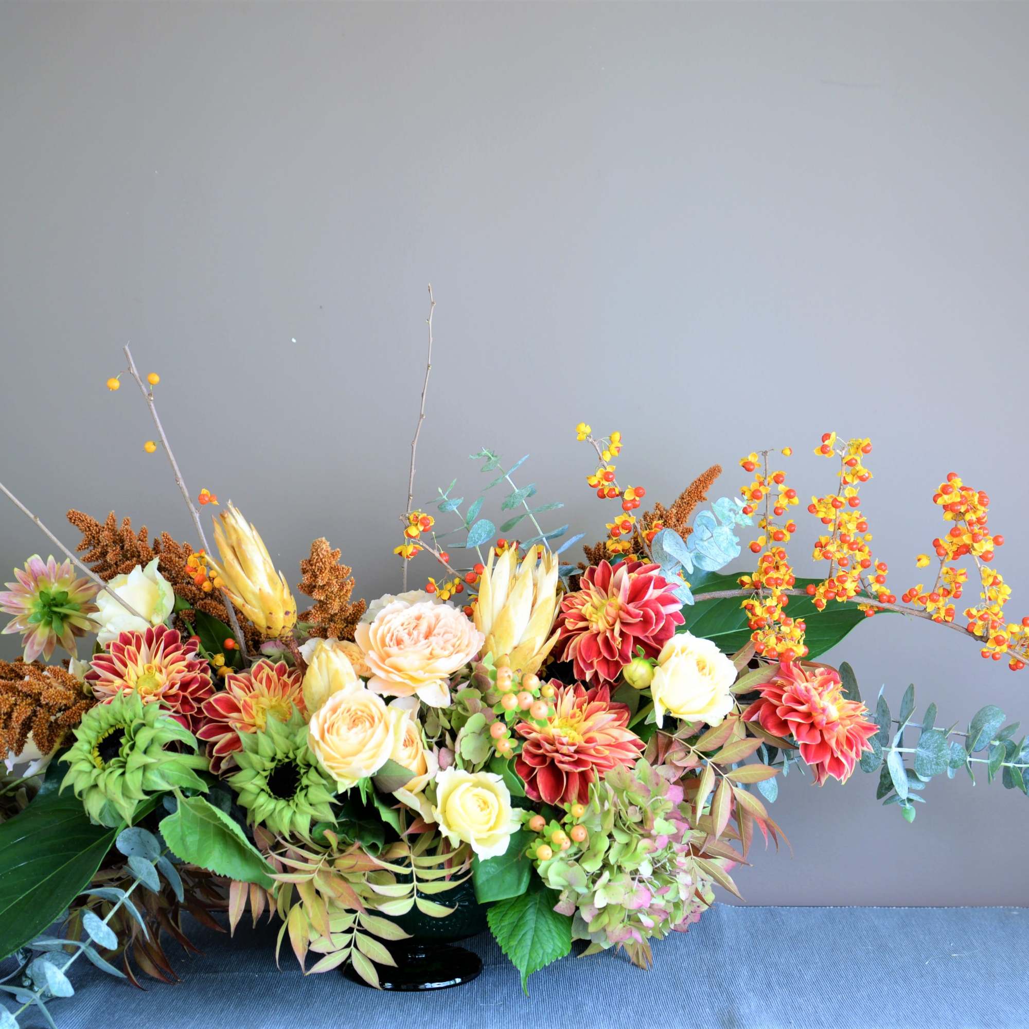 Large mixed floral arrangement in a black vase with orange berries