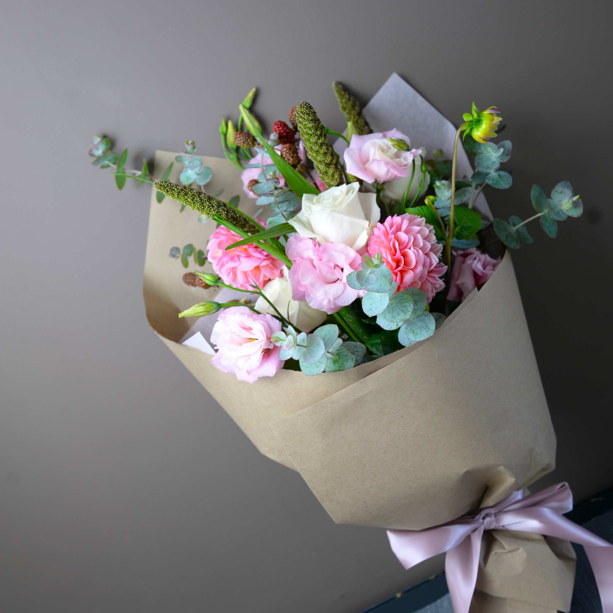 Bouquet of pink and white flowers wrapped in kraft paper with a lavender ribbon
