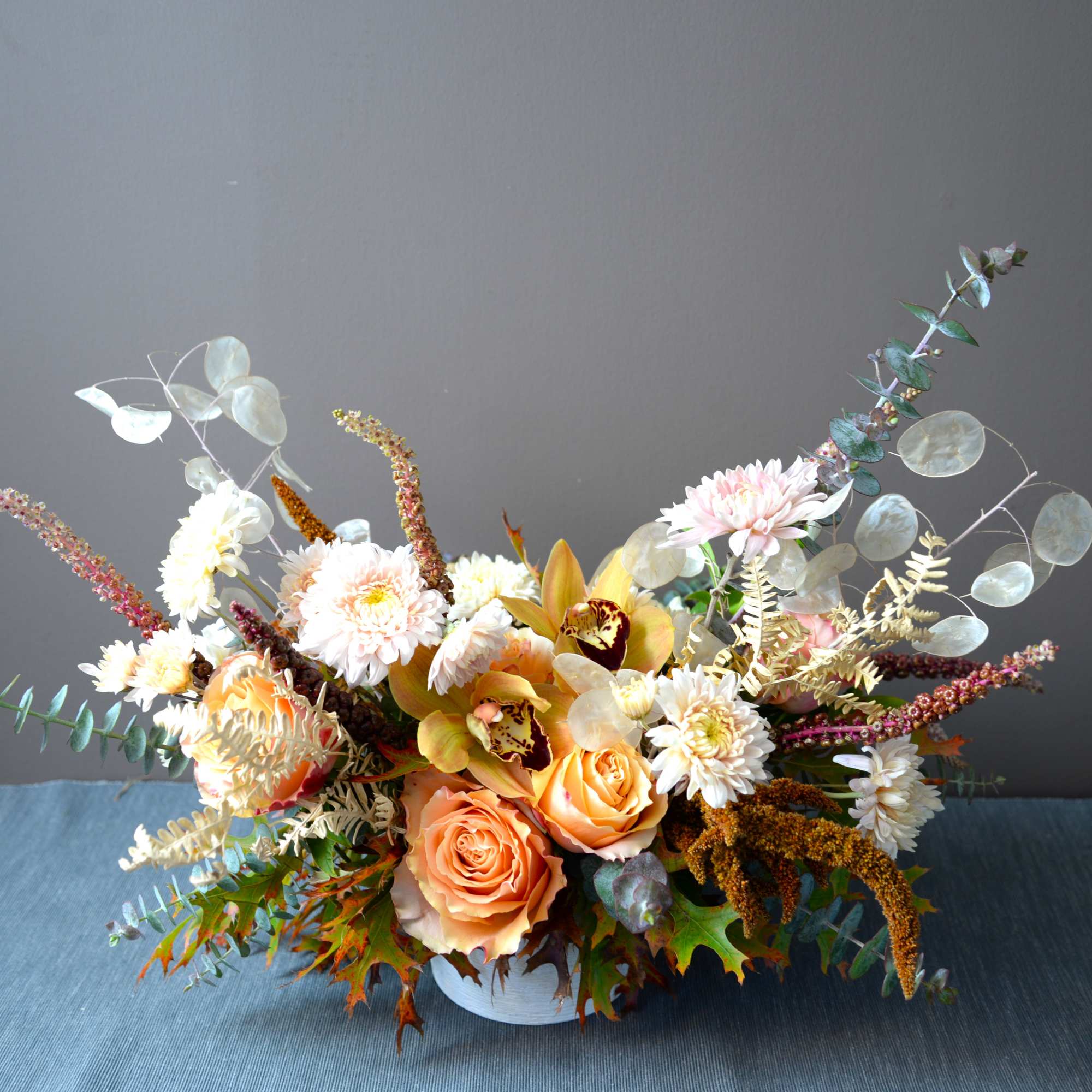 Peach roses and white chrysanthemums in a low white container