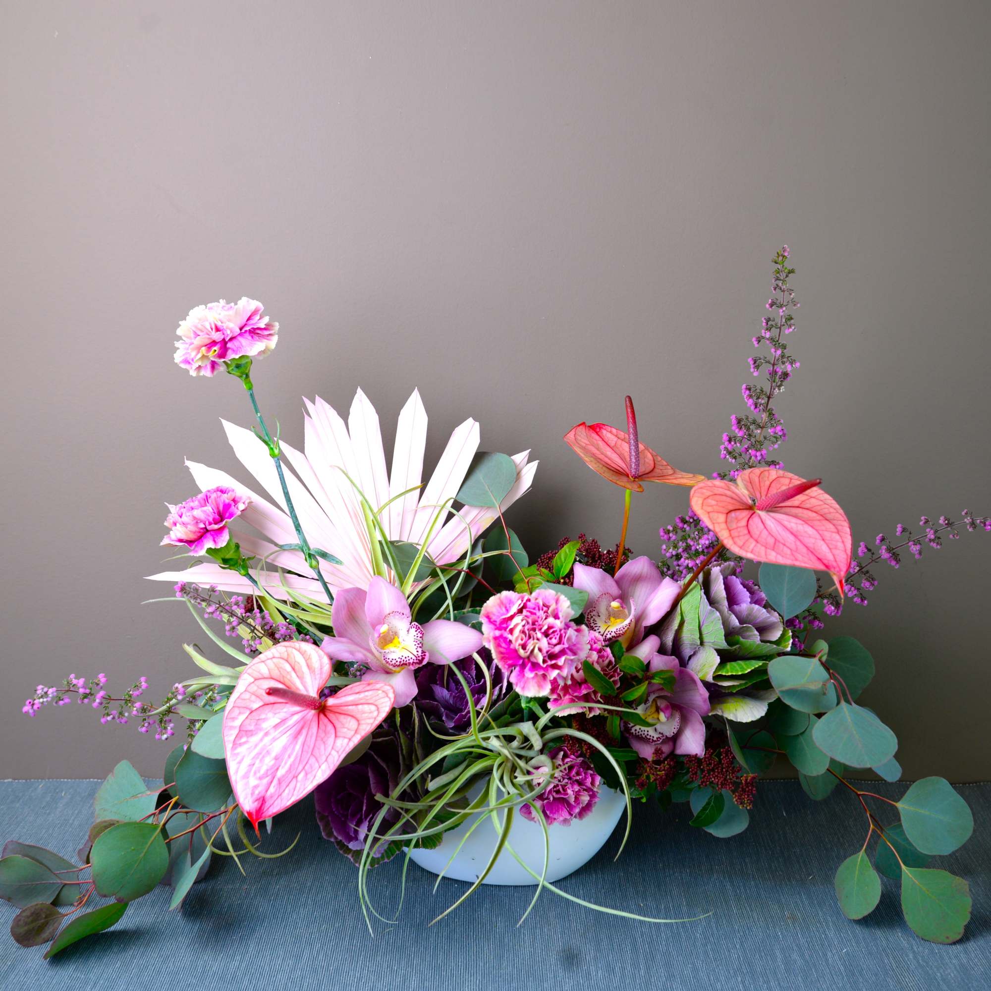 Pink and purple floral arrangement in a white bowl vase