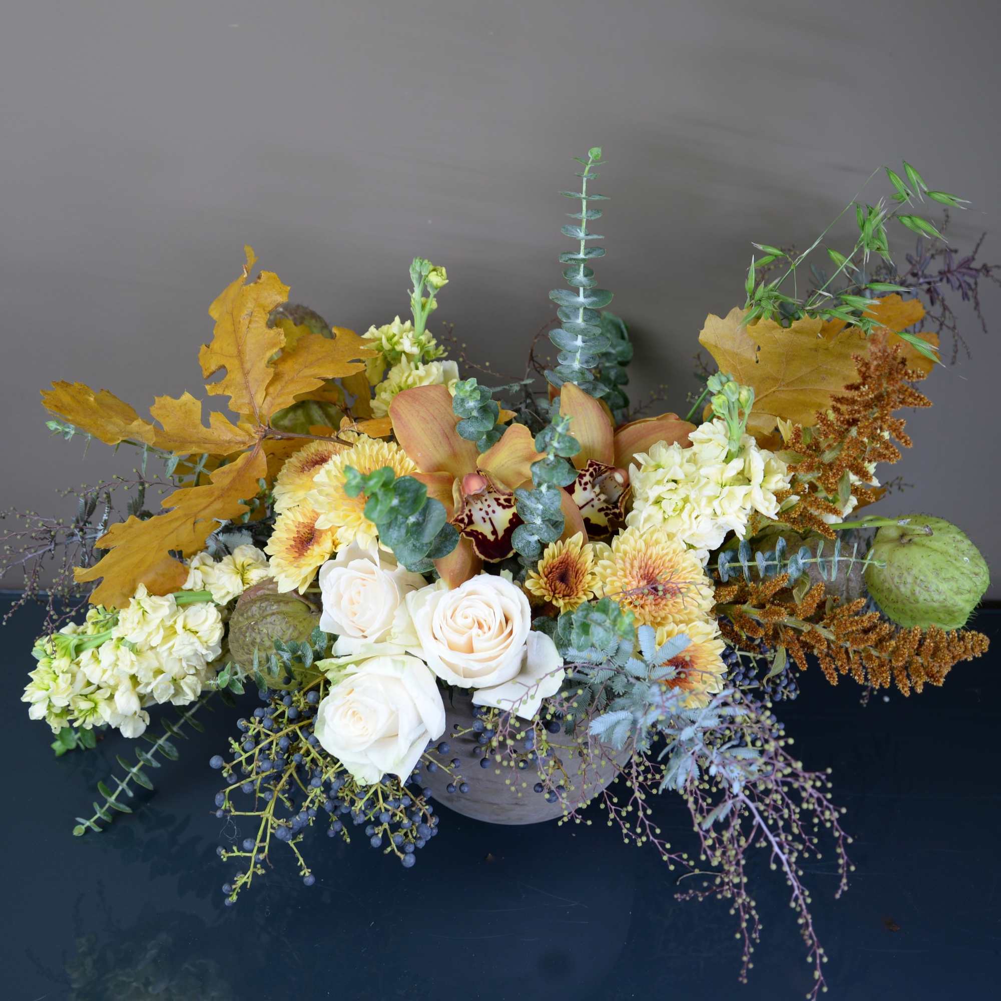 Autumn floral arrangement with white roses and yellow blooms in a low container