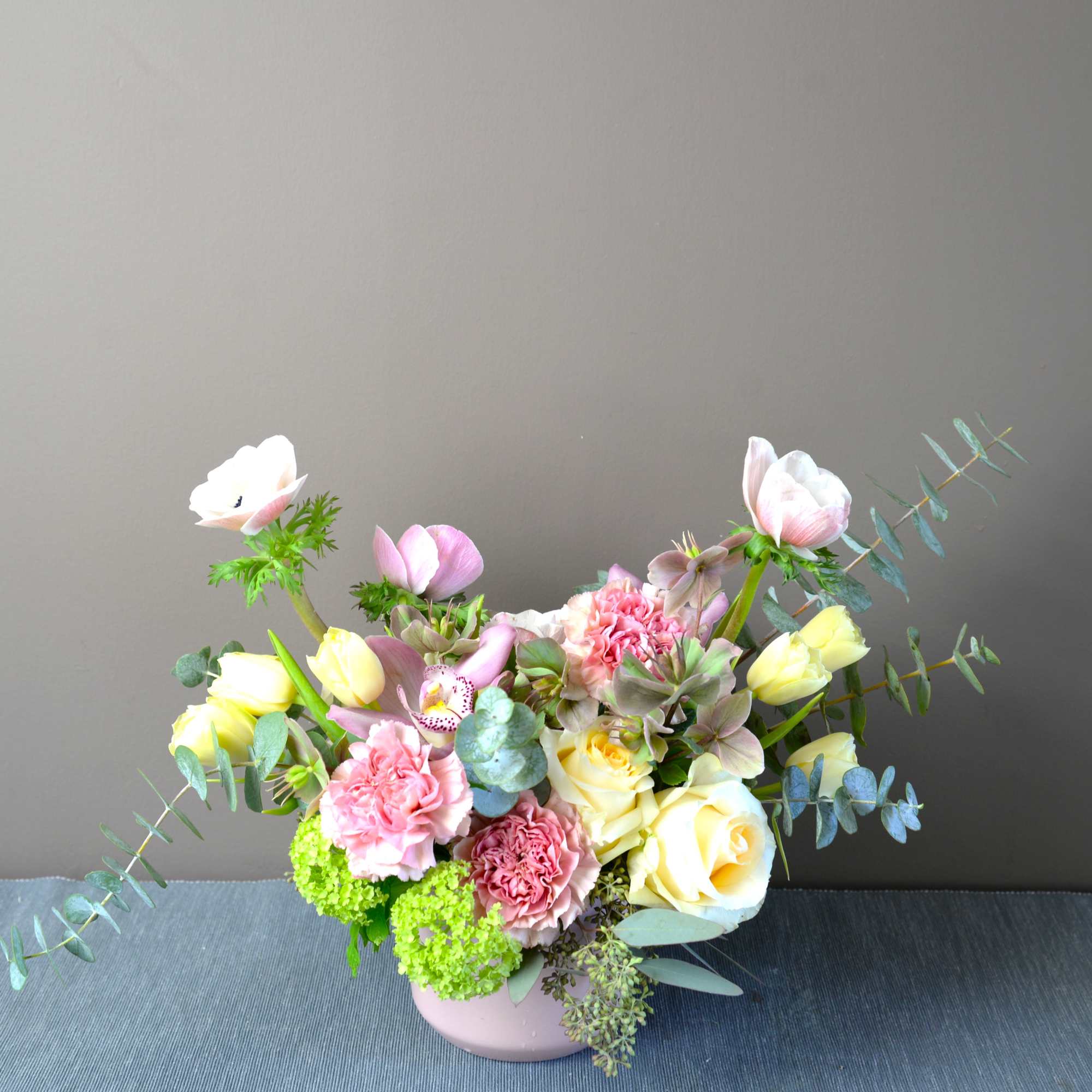 Pastel floral arrangement in a pink vase with roses, tulips, and carnations