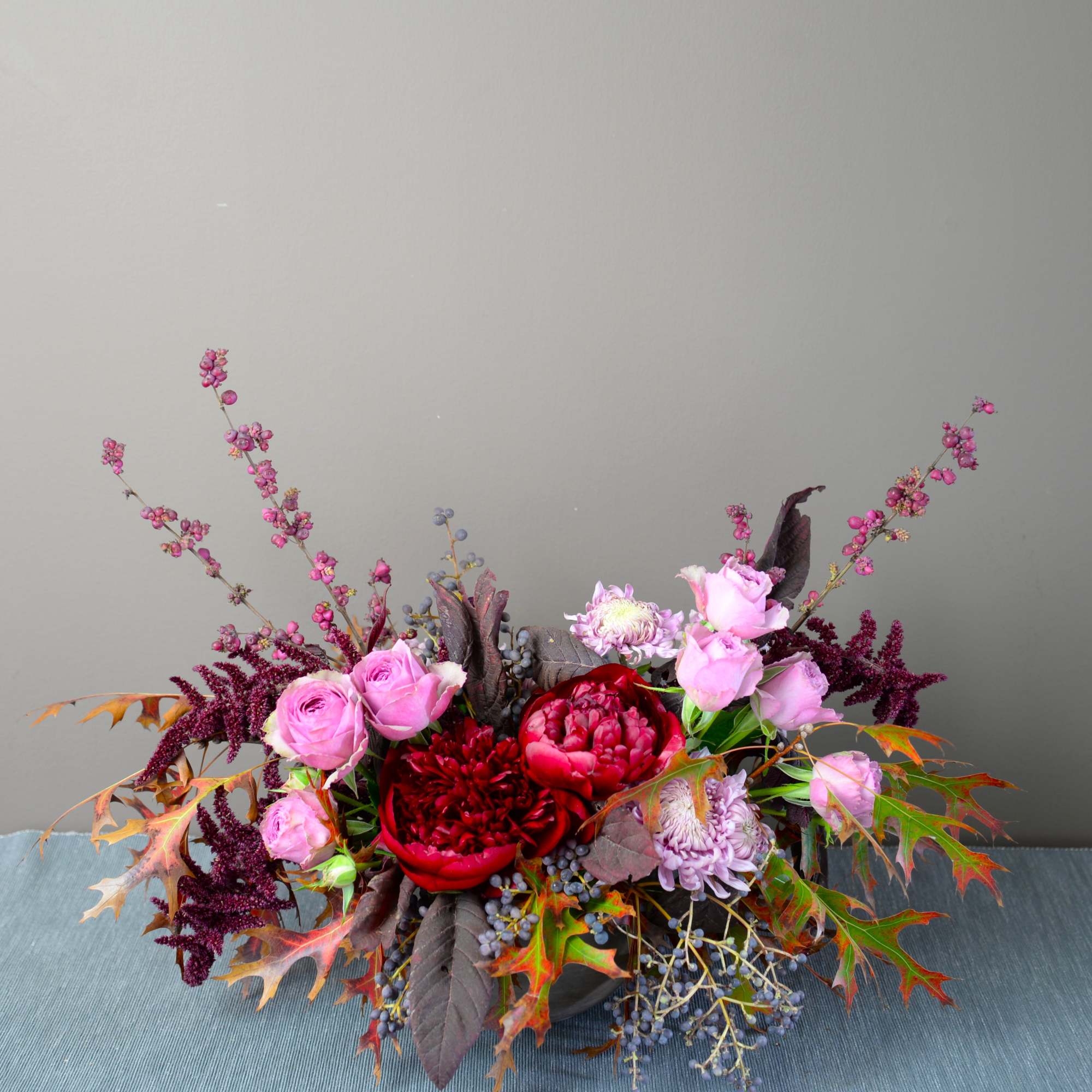 Low floral arrangement with pink roses and red blooms in a dark container