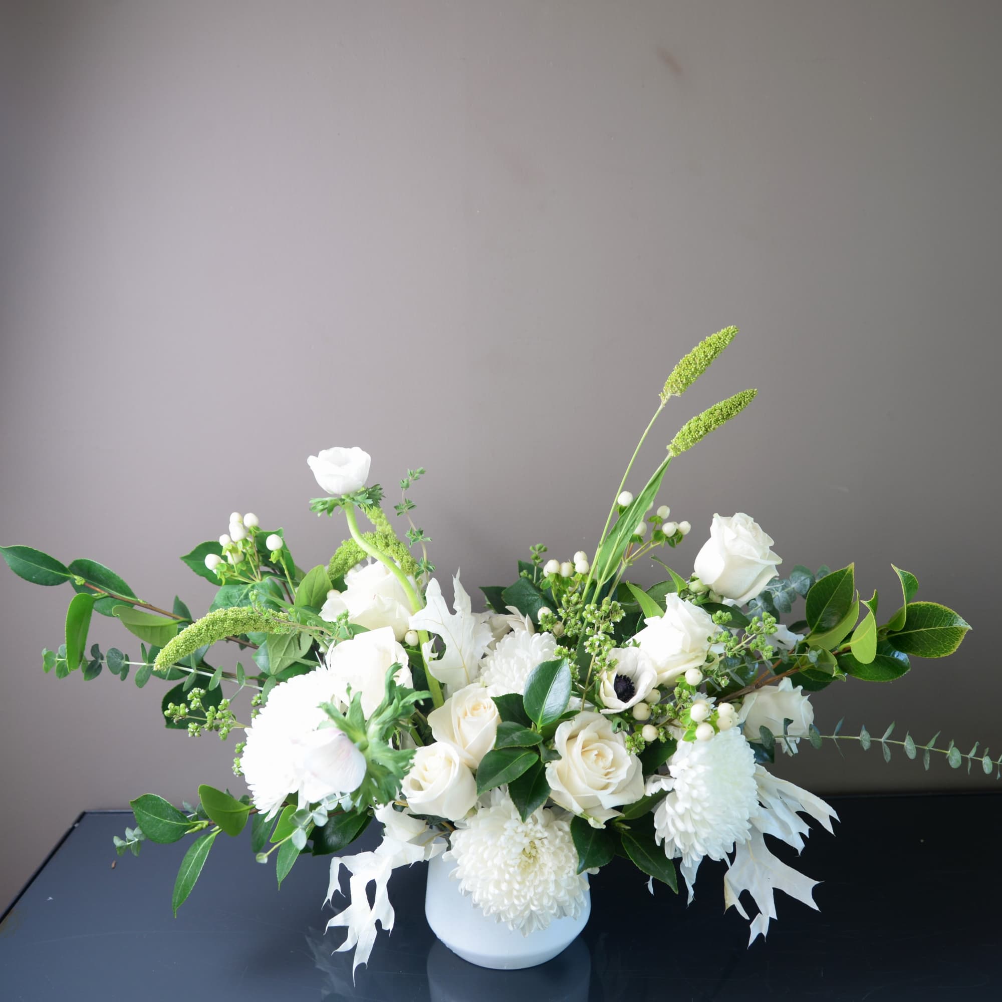 White floral arrangement in a white vase with green accents