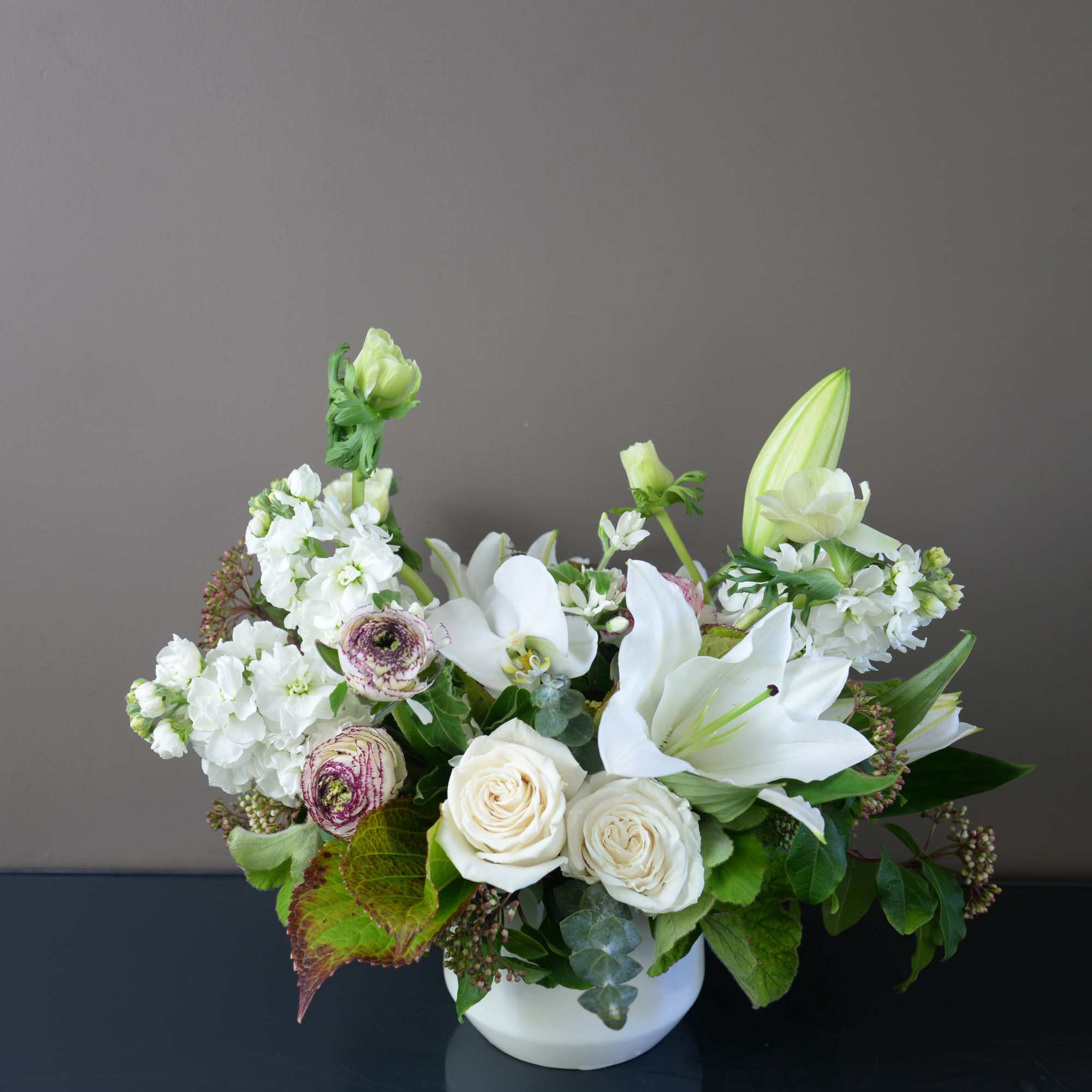 White roses and lilies arranged in a white vase