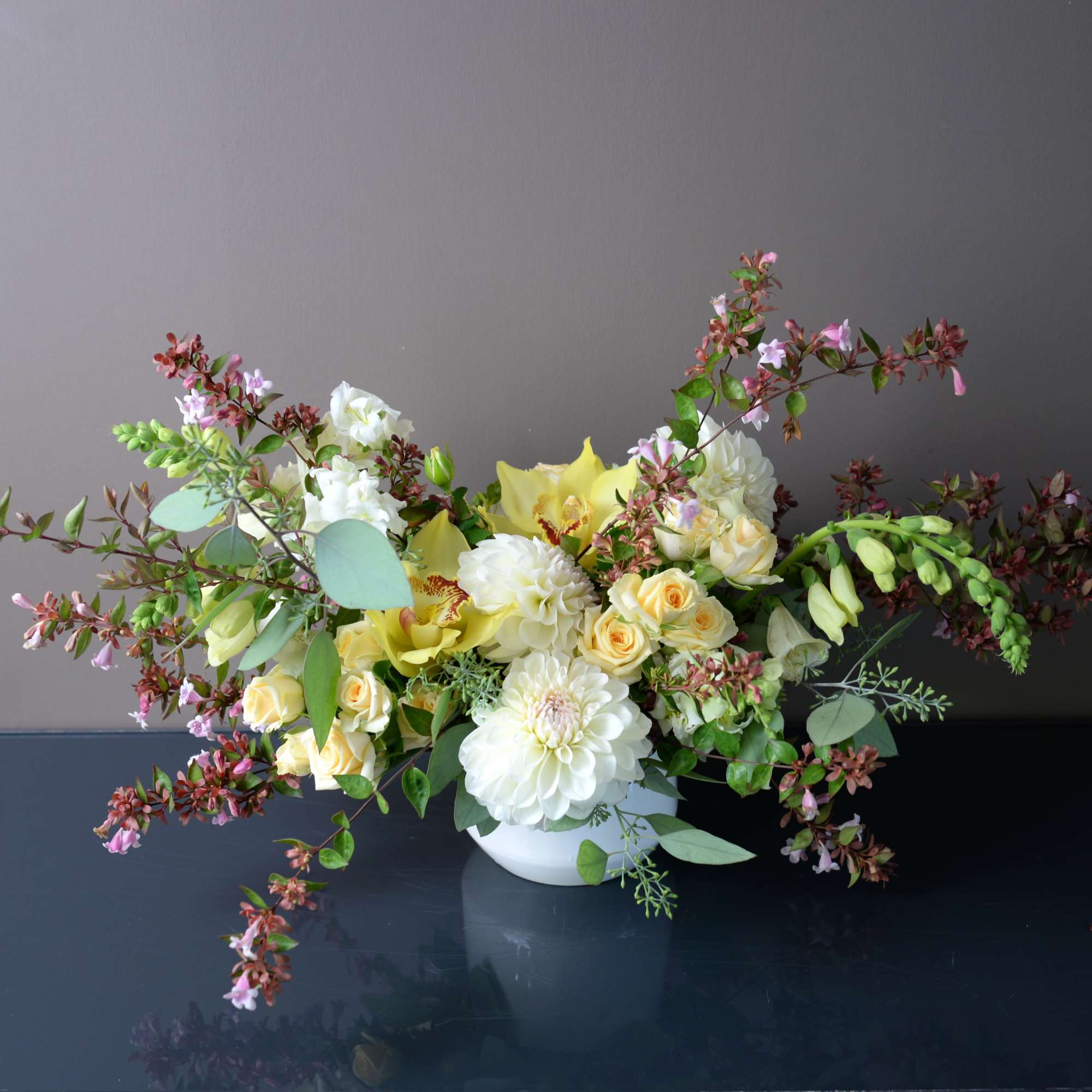 White and pale yellow floral arrangement in a white bowl vase