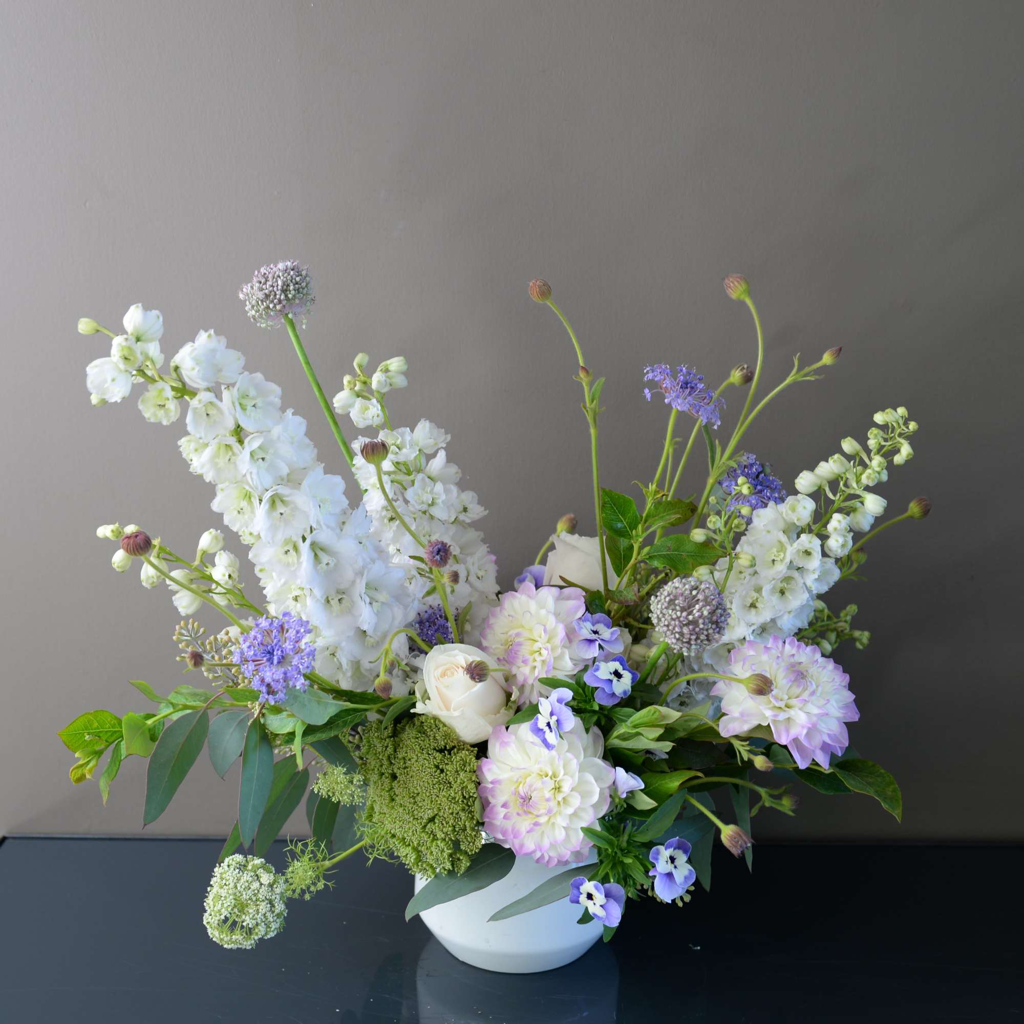 Pastel floral arrangement in a white bowl vase with white and lavender blooms