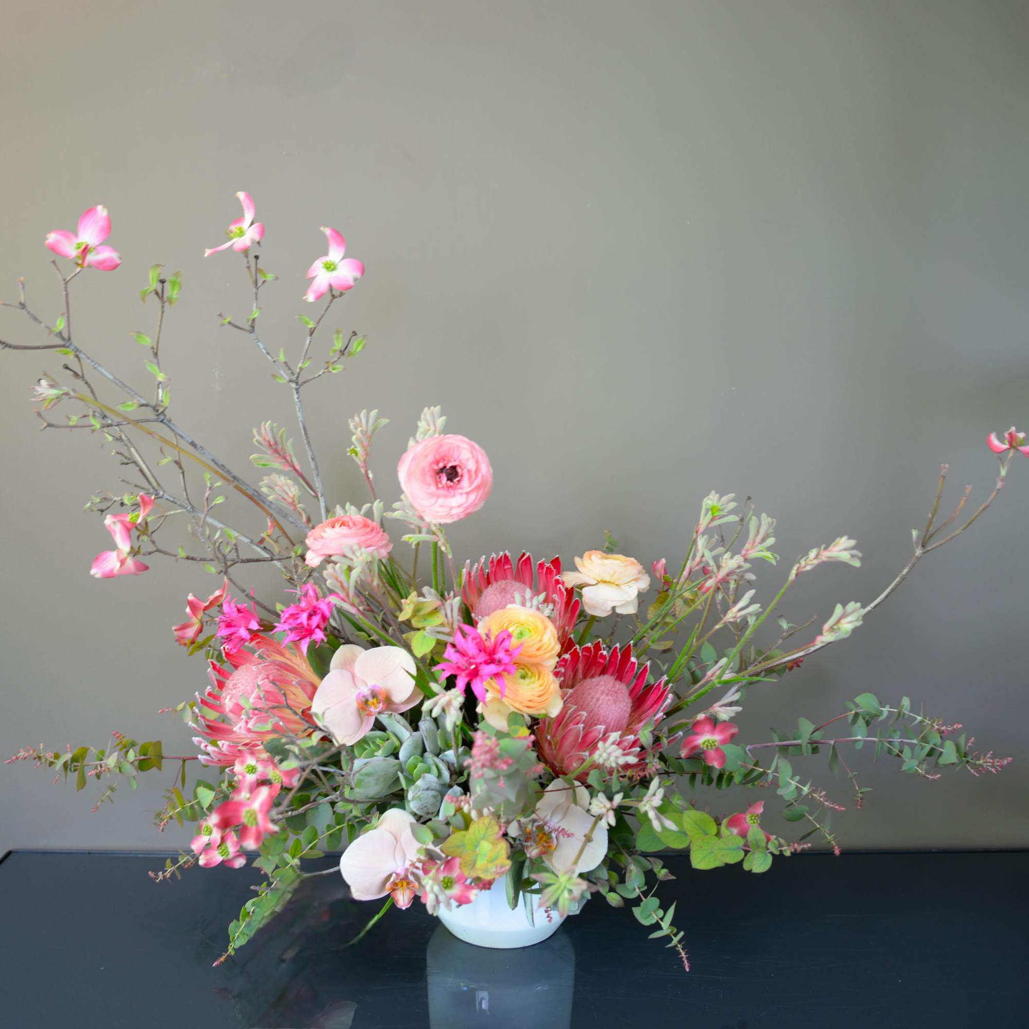Pink and white floral arrangement in a white vase with branching stems