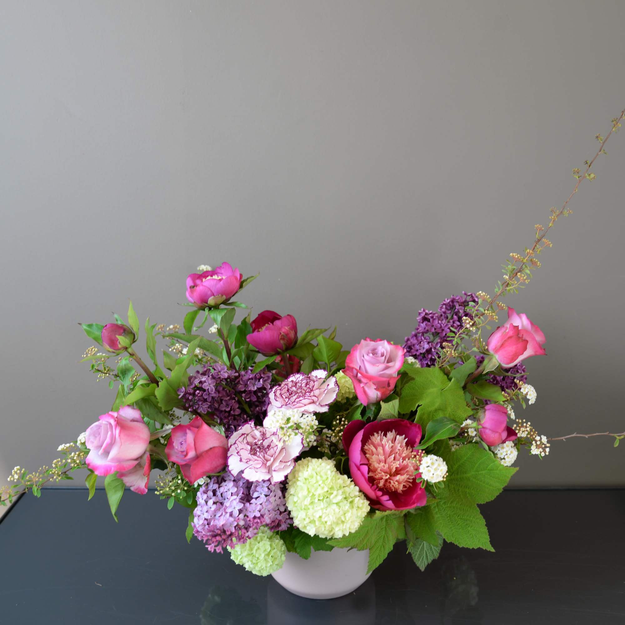 Pink and purple floral arrangement in a white bowl vase