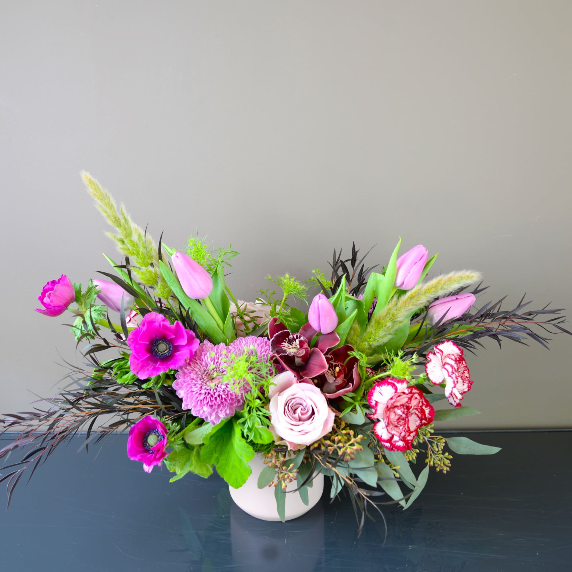 Pink and purple mixed flower arrangement in a white vase