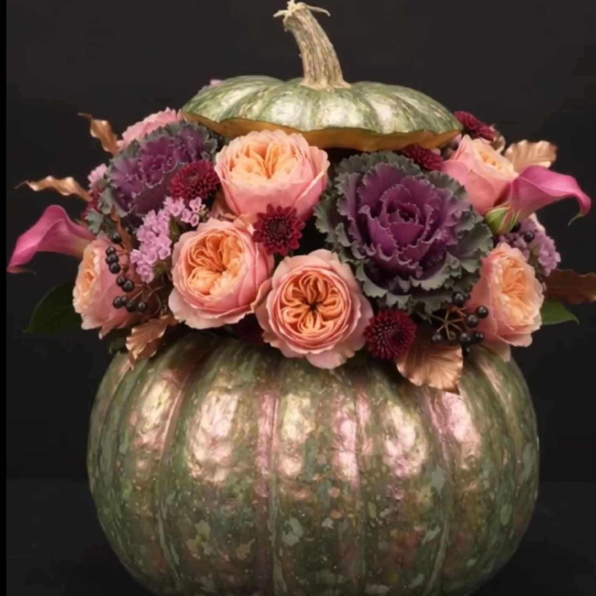 Floral arrangement in a painted pumpkin with pink and purple blooms
