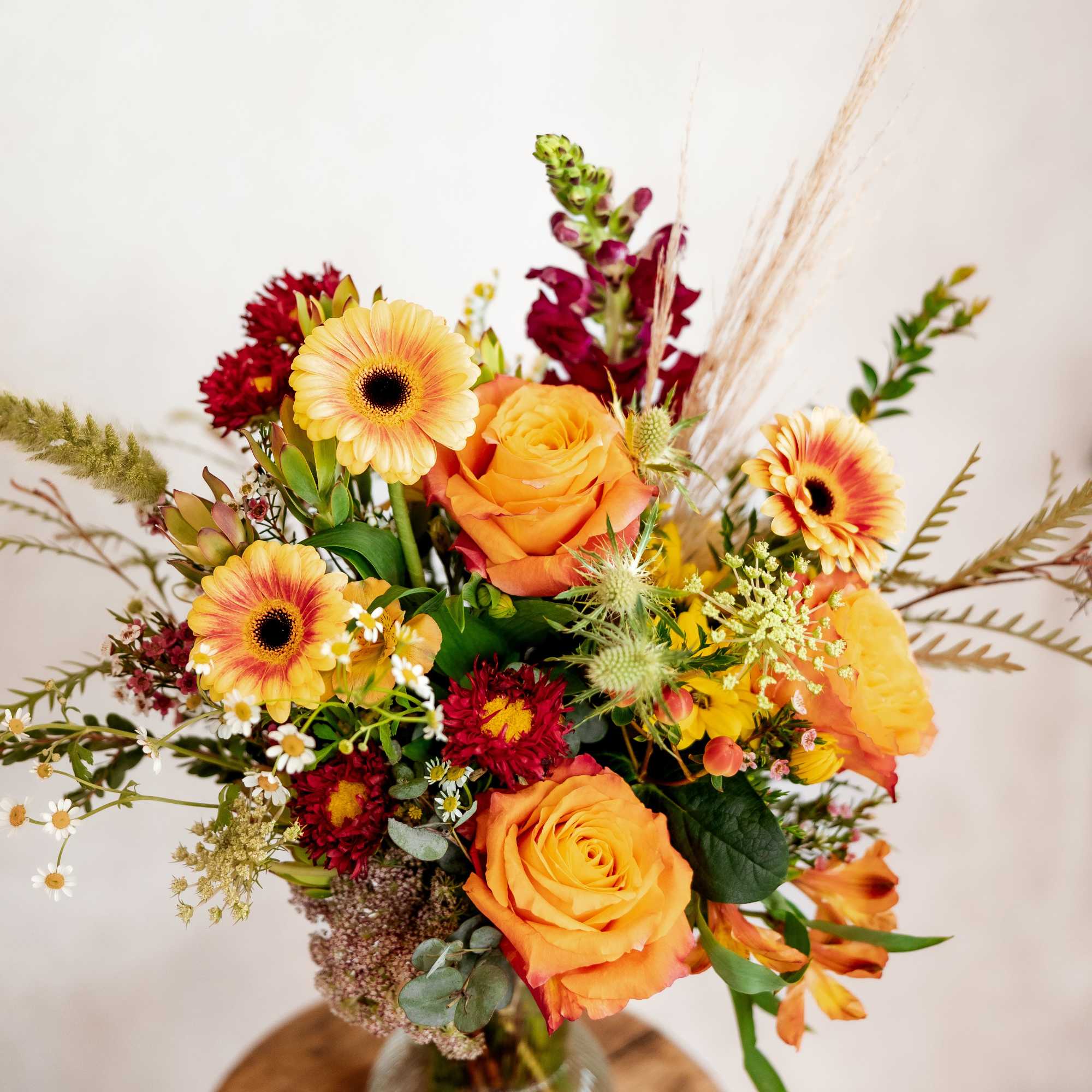 Orange roses and gerbera daisies in a glass vase