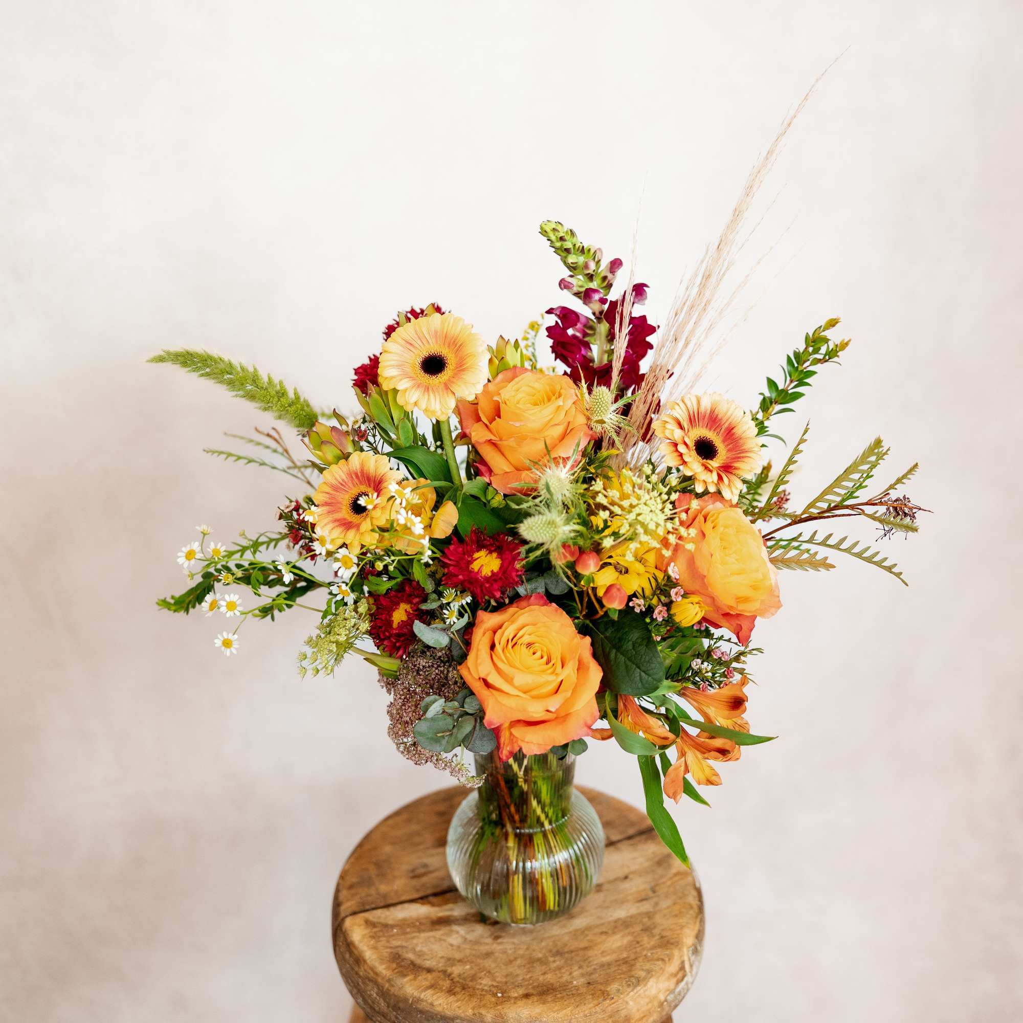 Bouquet of orange roses and mixed flowers in a glass vase