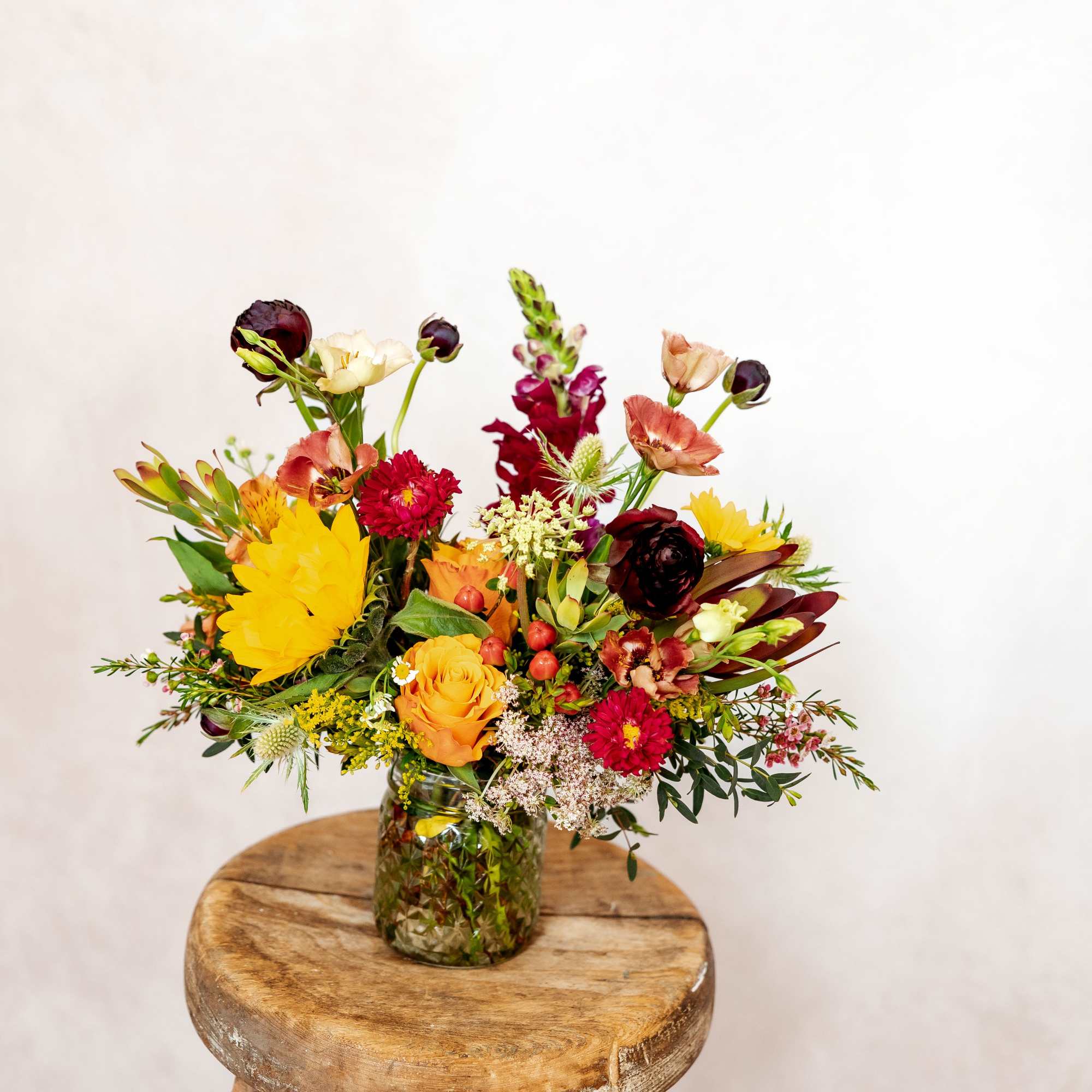 Colorful mixed flower arrangement in a textured glass vase