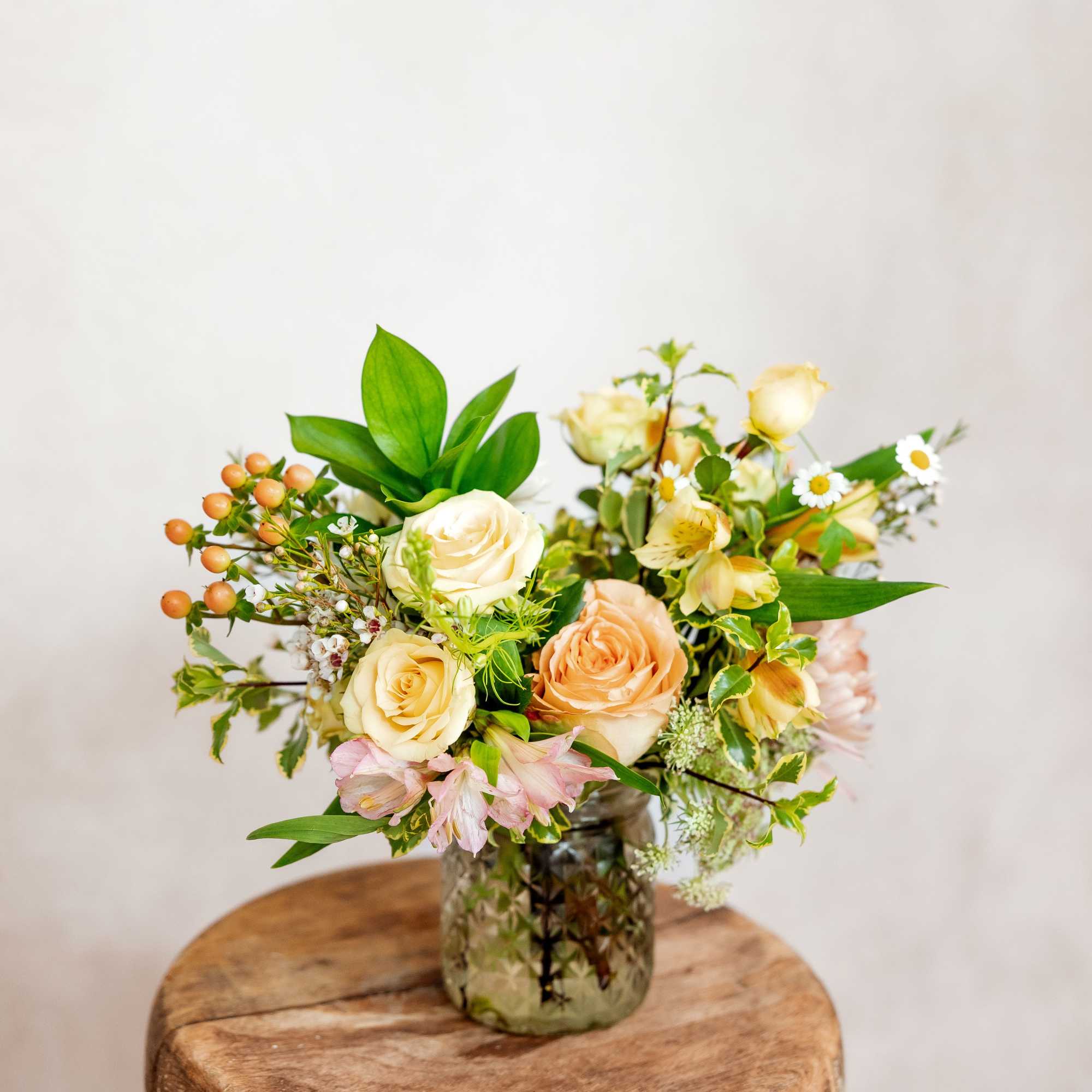 Cream and peach roses in a glass vase with small white flowers