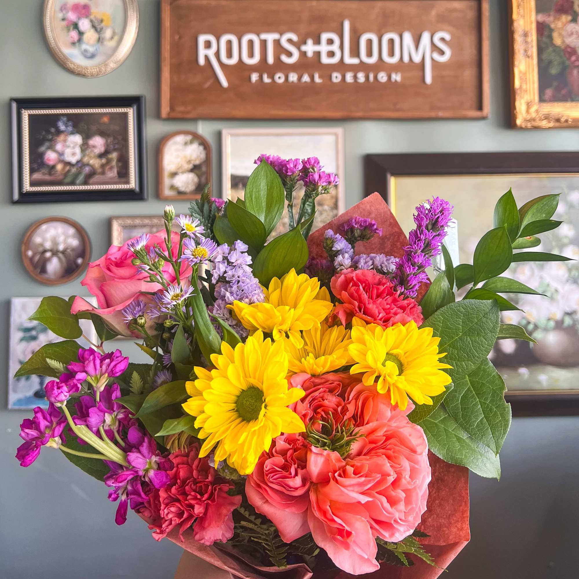 Handheld bouquet of pink, yellow, and coral flowers
