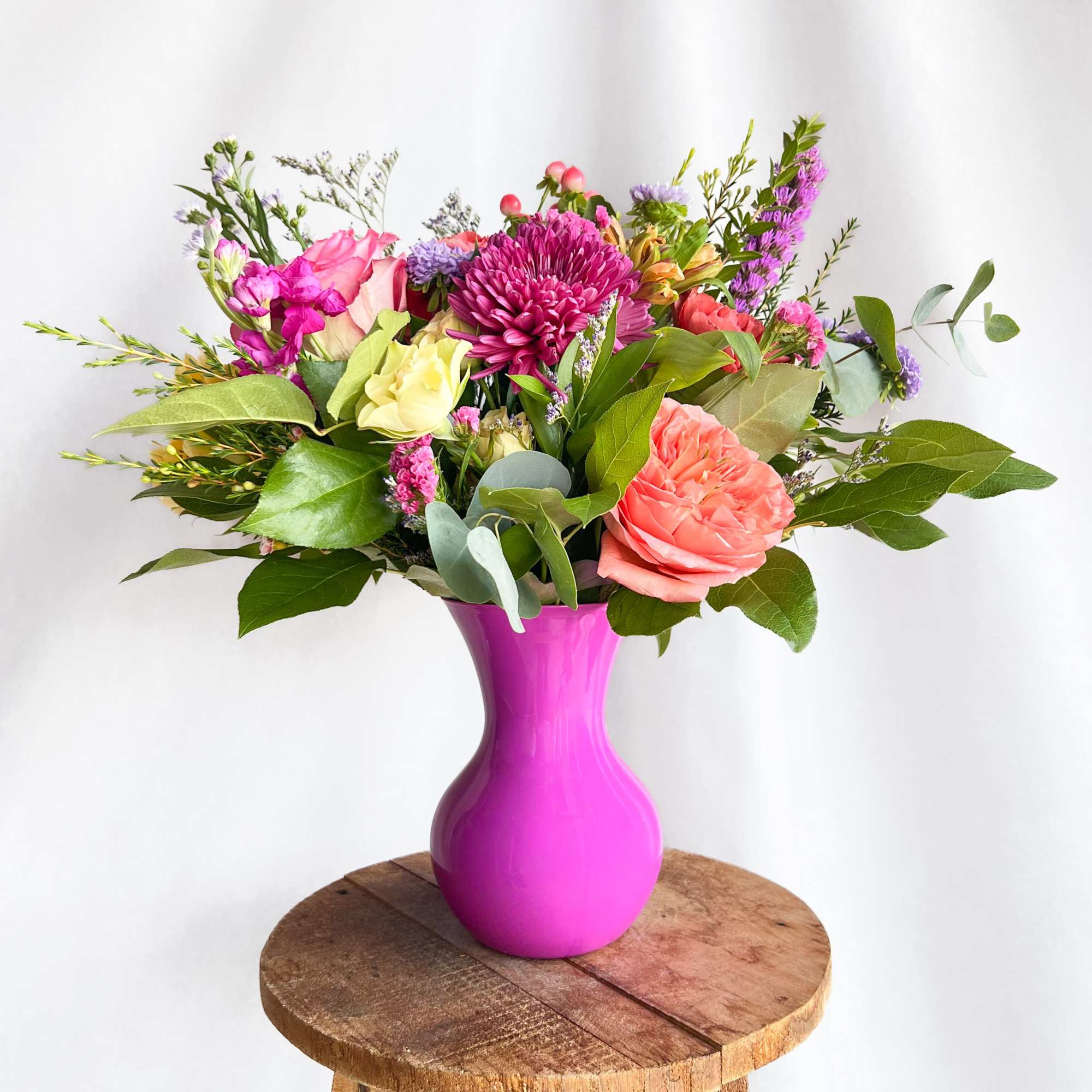 Mixed pink and purple bouquet in a bright magenta vase