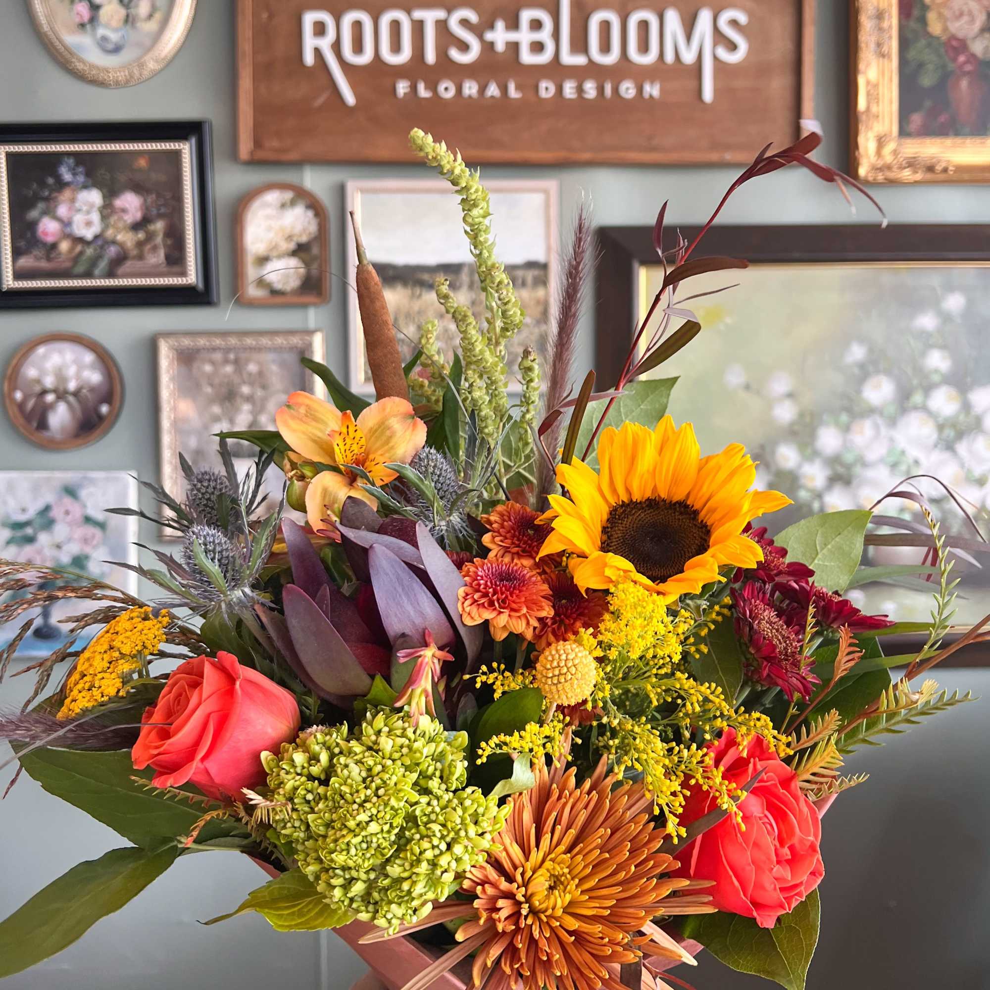 Handheld bouquet with sunflowers, roses, and chrysanthemums in warm fall colors