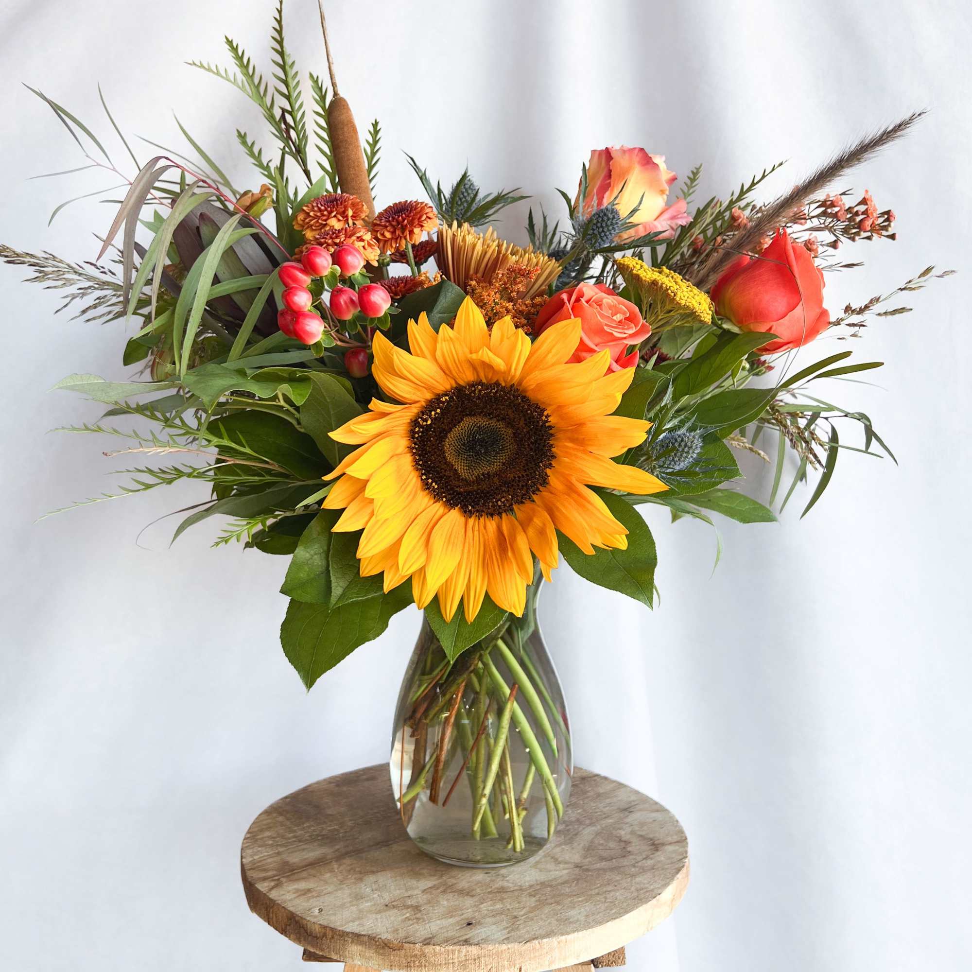Sunflower bouquet with orange roses in a glass vase