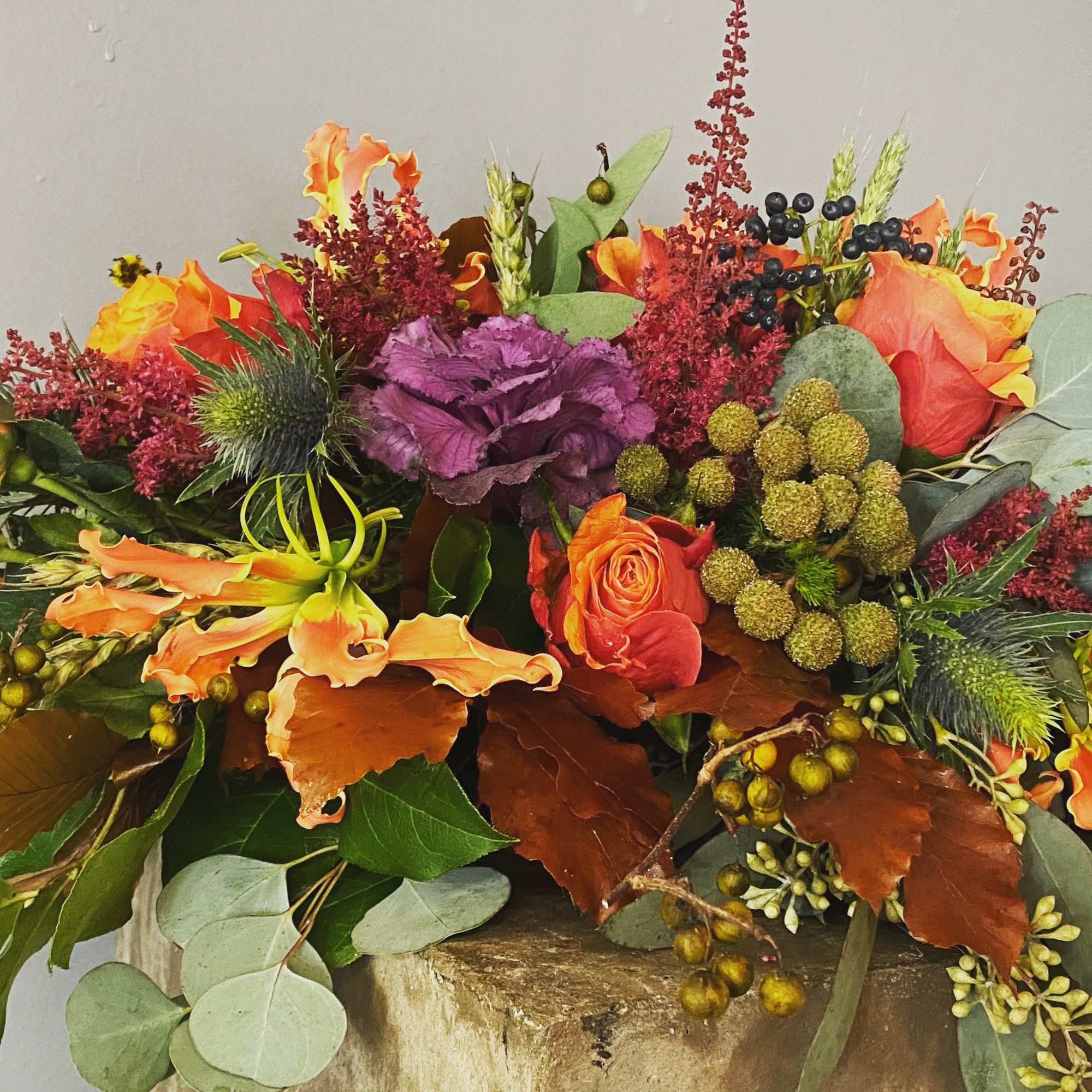 Mixed bouquet with orange roses and purple blooms in a low arrangement