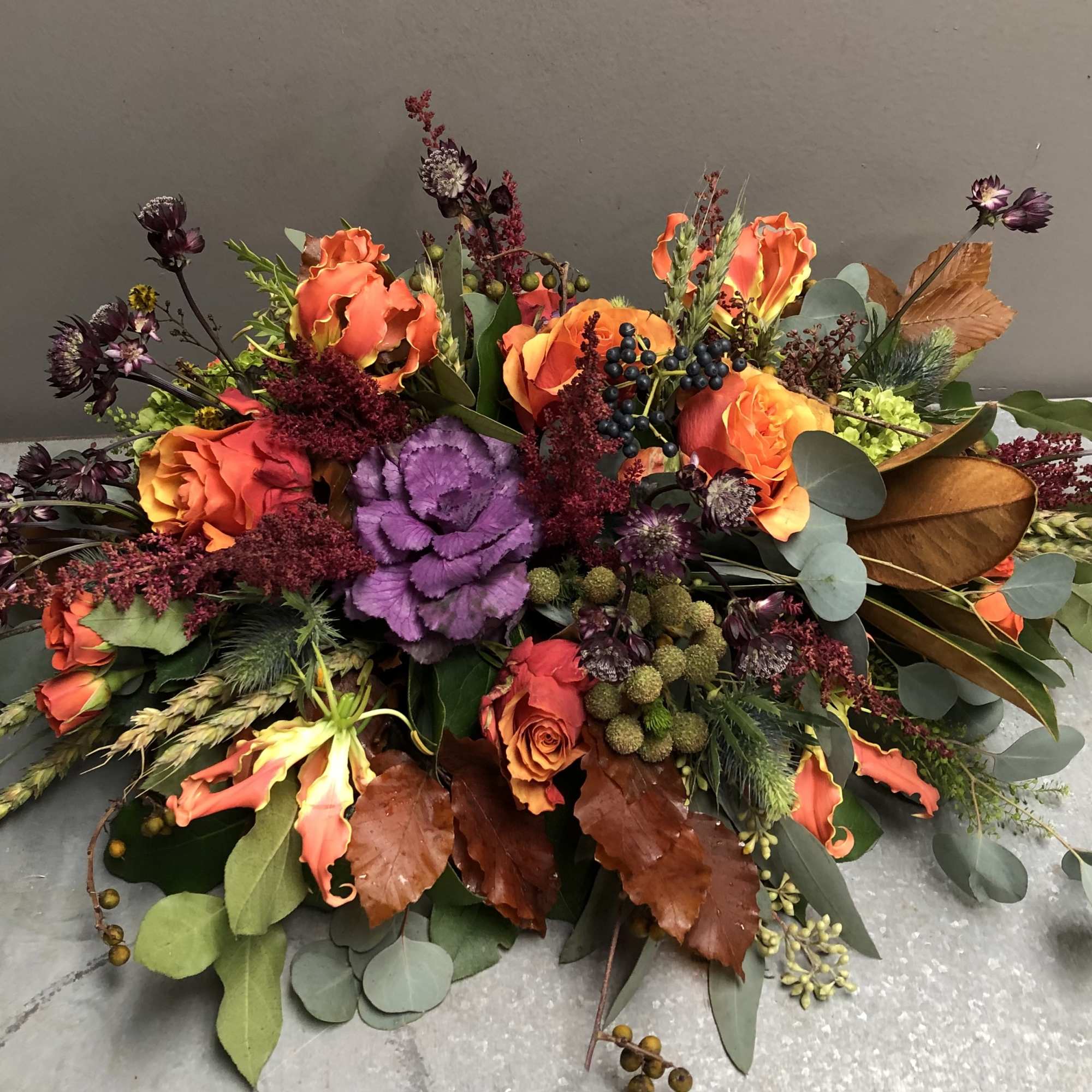Low floral arrangement with orange roses and purple cabbage in a shallow design
