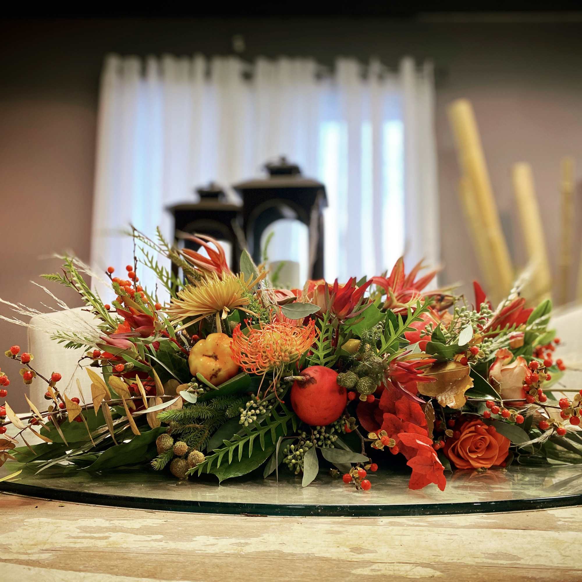 Low floral centerpiece with orange and red blooms on a glass tray