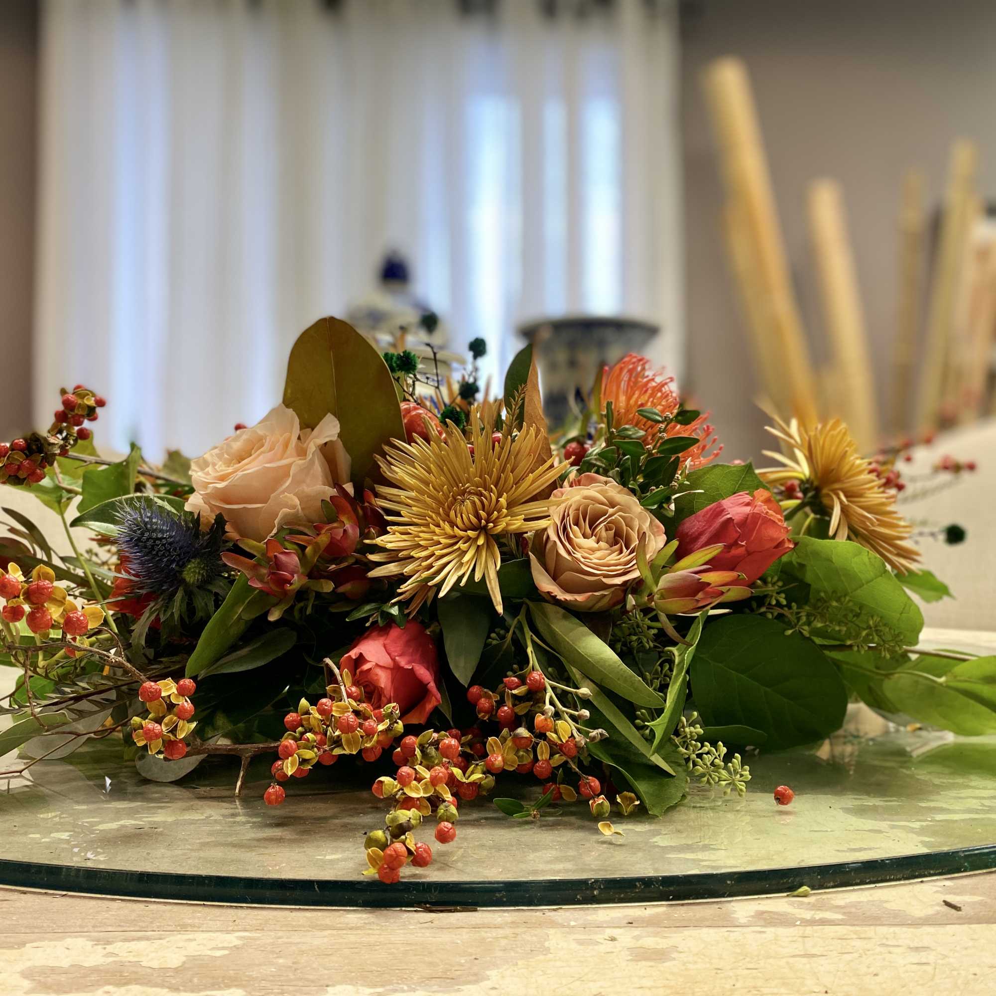 Low floral centerpiece with peach roses and gold chrysanthemum blooms