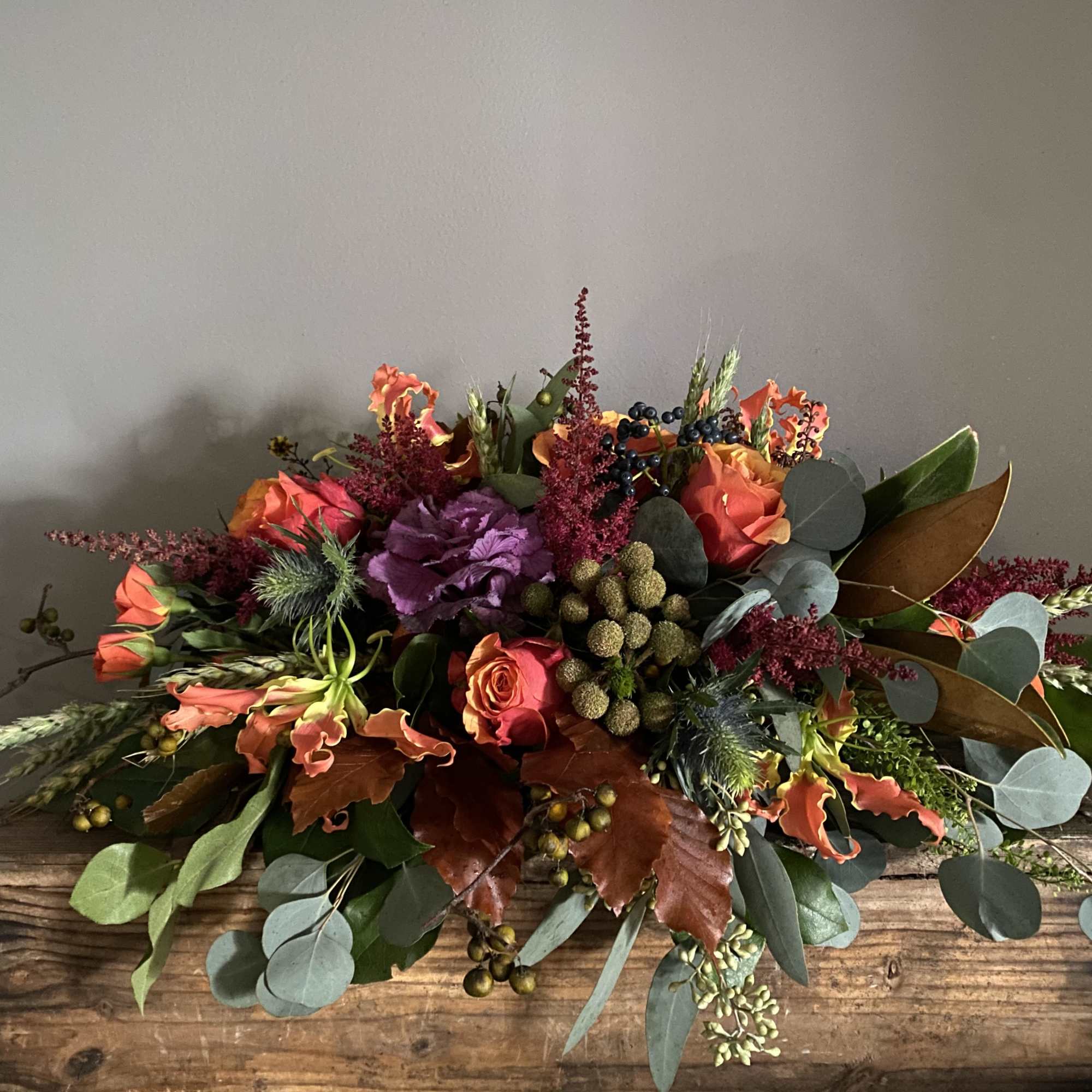 Autumn floral arrangement with orange and purple blooms in a wooden box