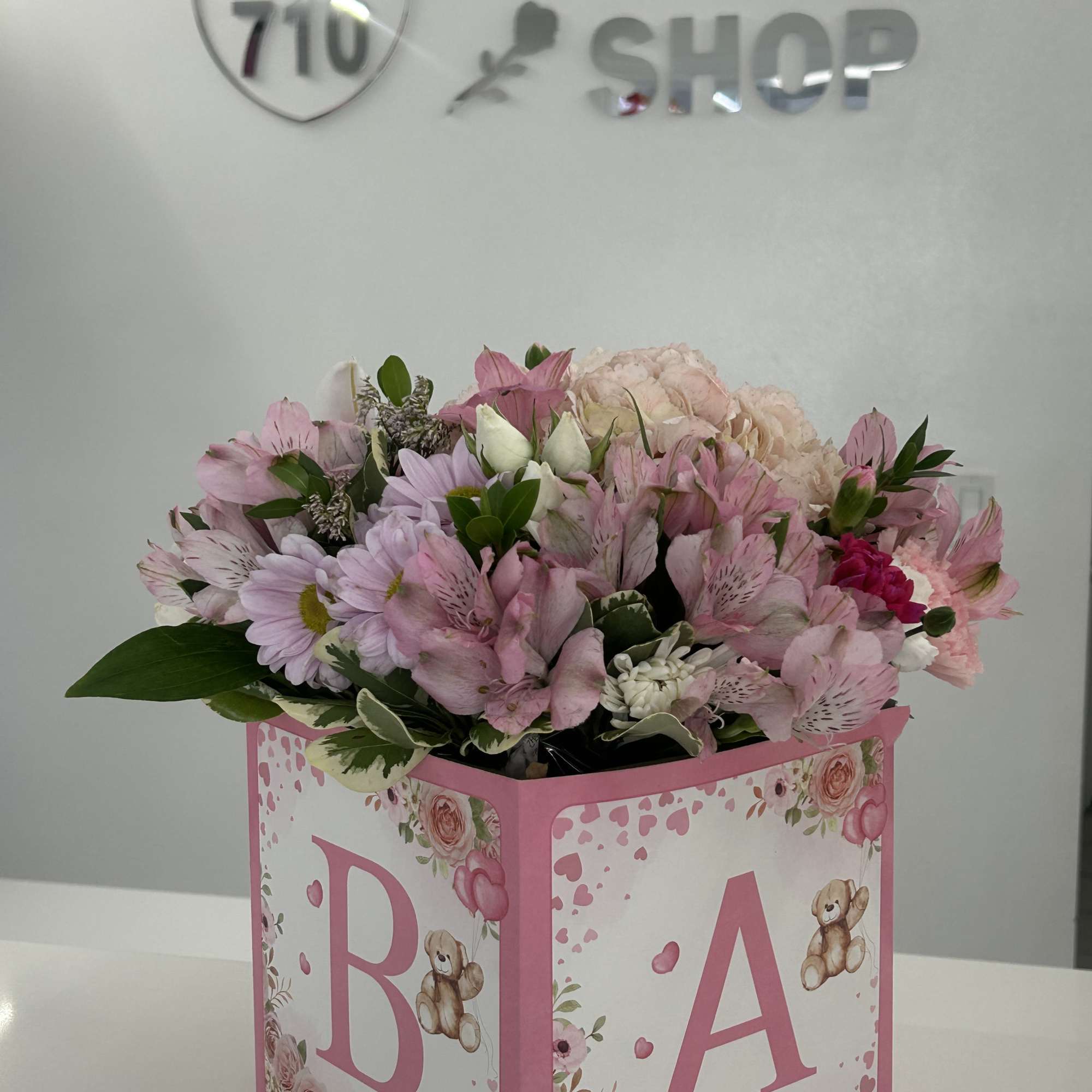 Pink and white bouquet in a decorated baby gift box with the letters B and A