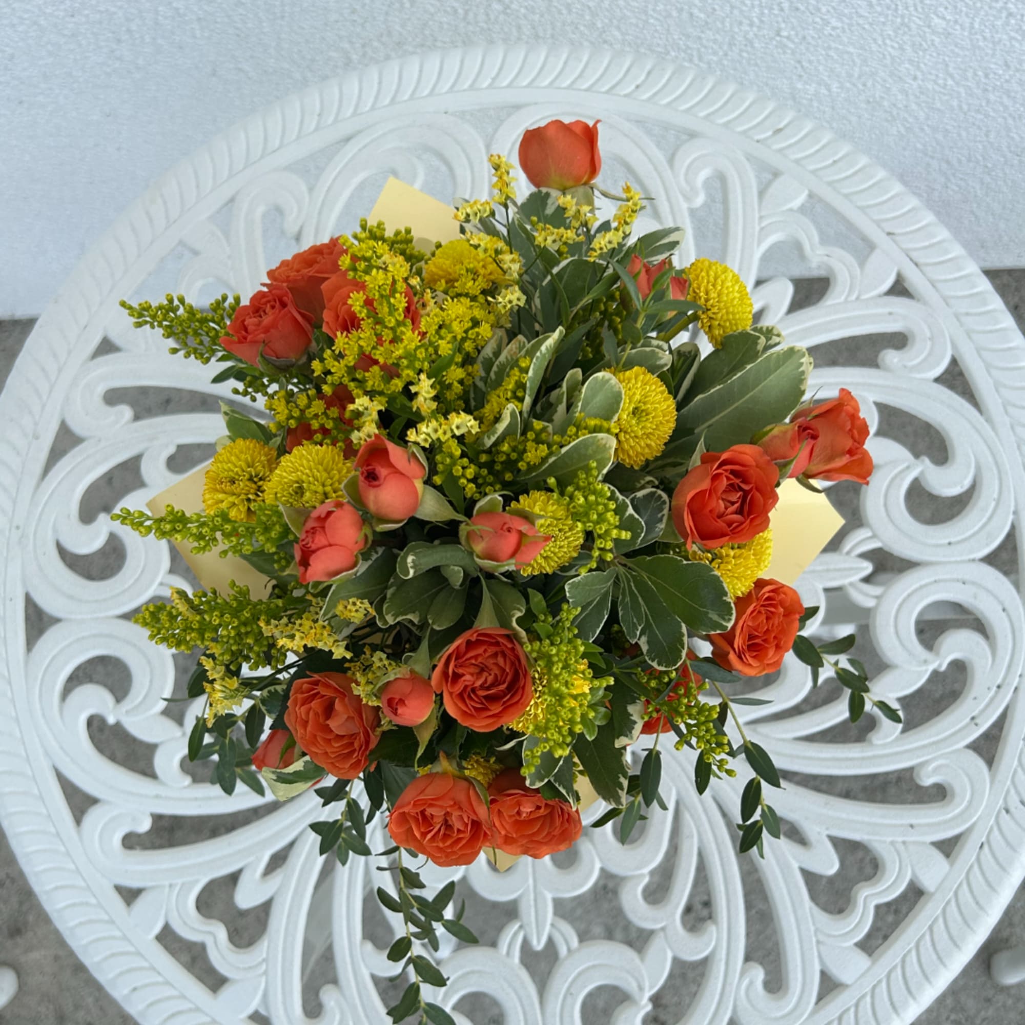Orange roses and yellow pompon flowers in a compact bouquet