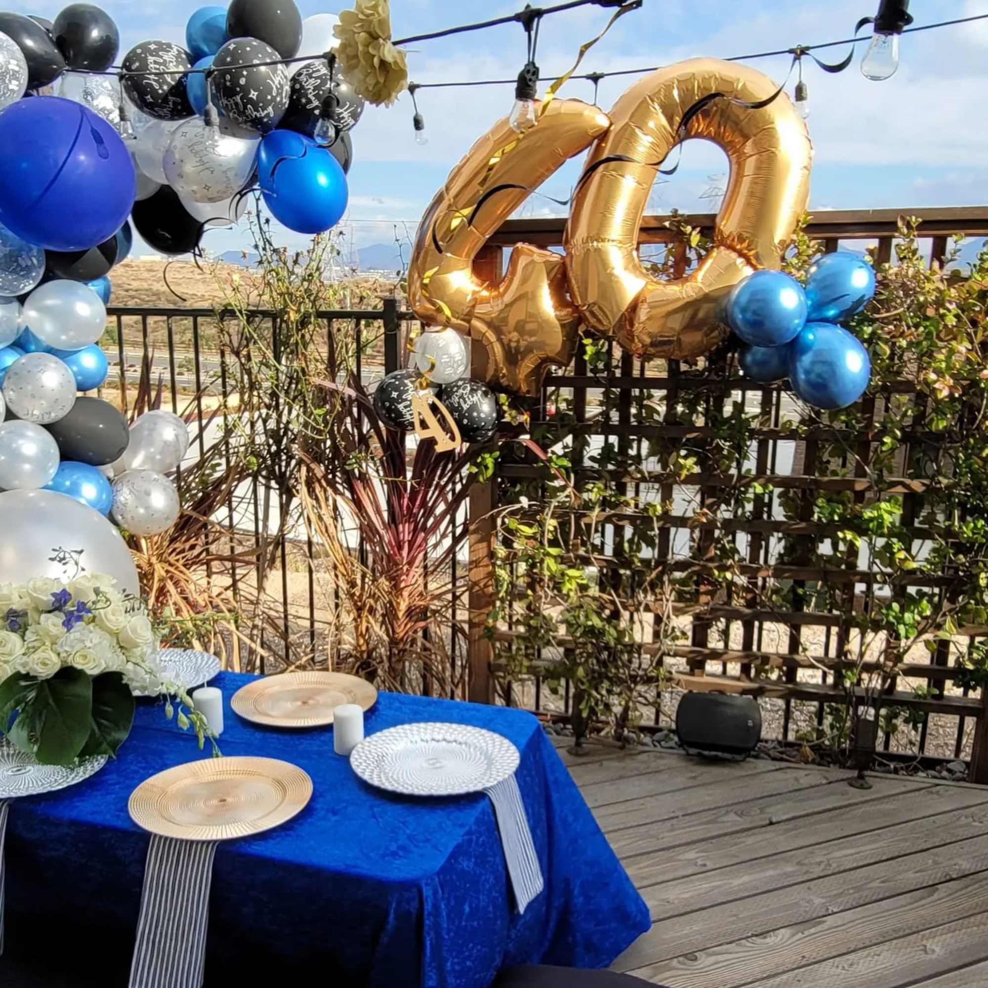 Birthday party setup with balloon arches, gold "40" balloons, and floral centerpieces