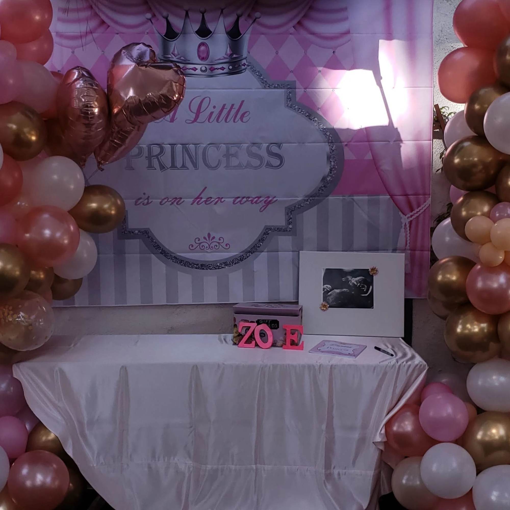 Pink, white, and gold balloon arch around a princess-themed party backdrop