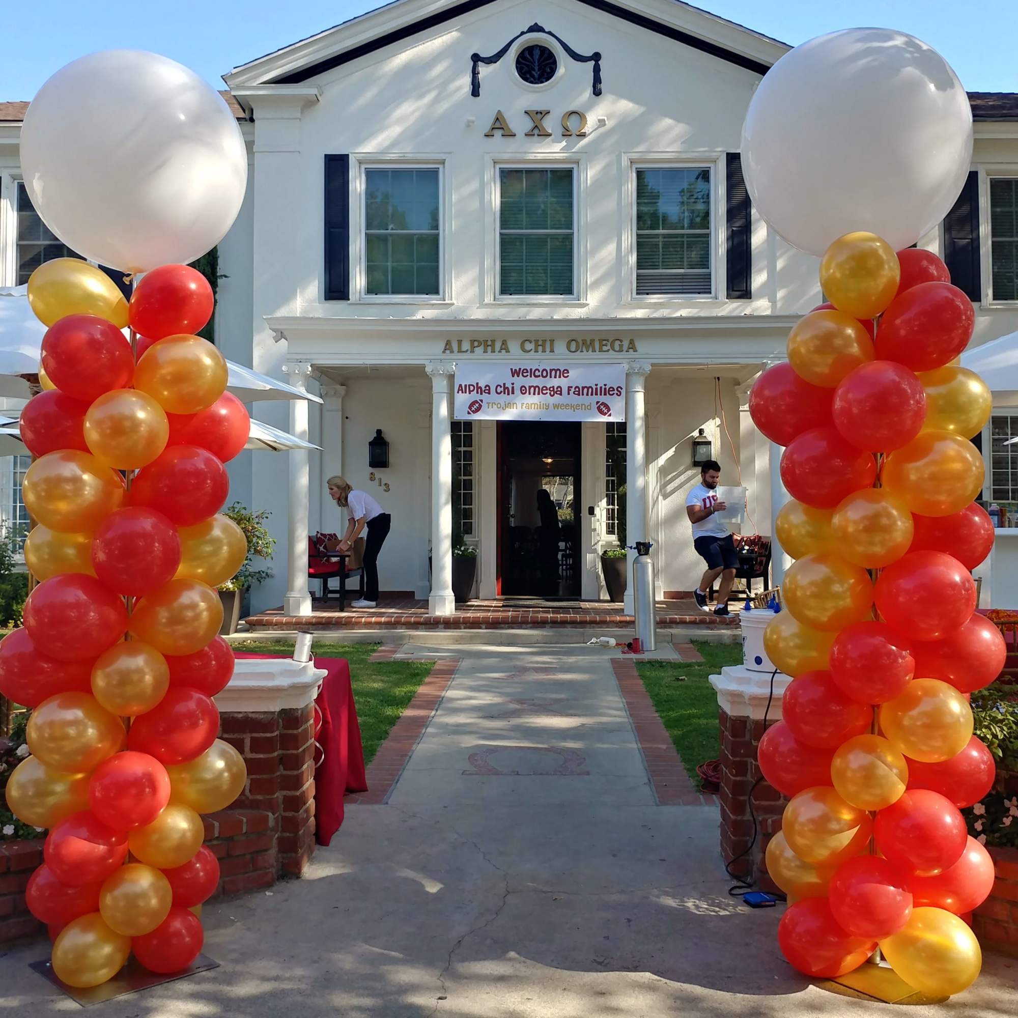 Red, orange, and gold balloon columns frame a house entrance