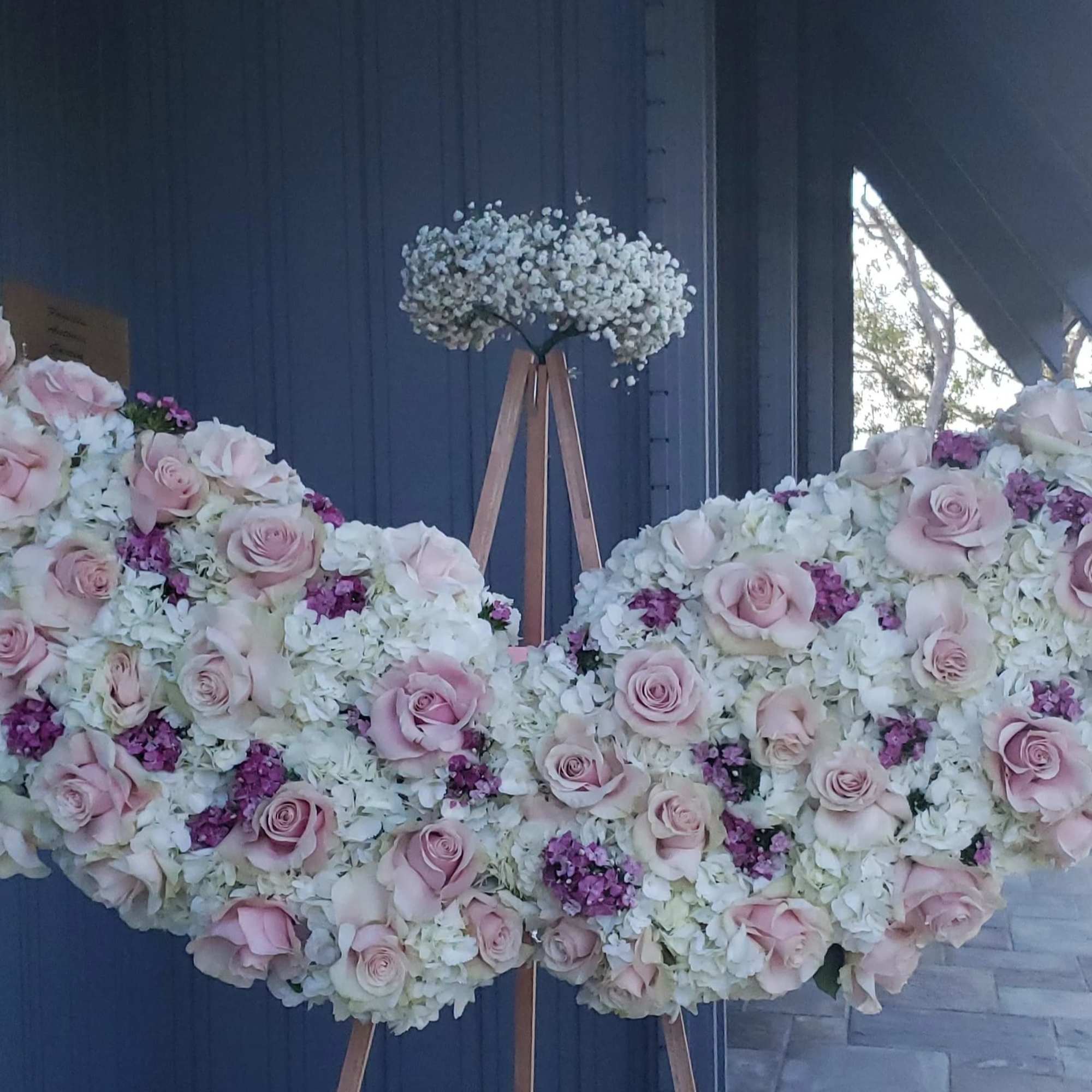 Large floral wing display with pink roses and white blooms on an easel