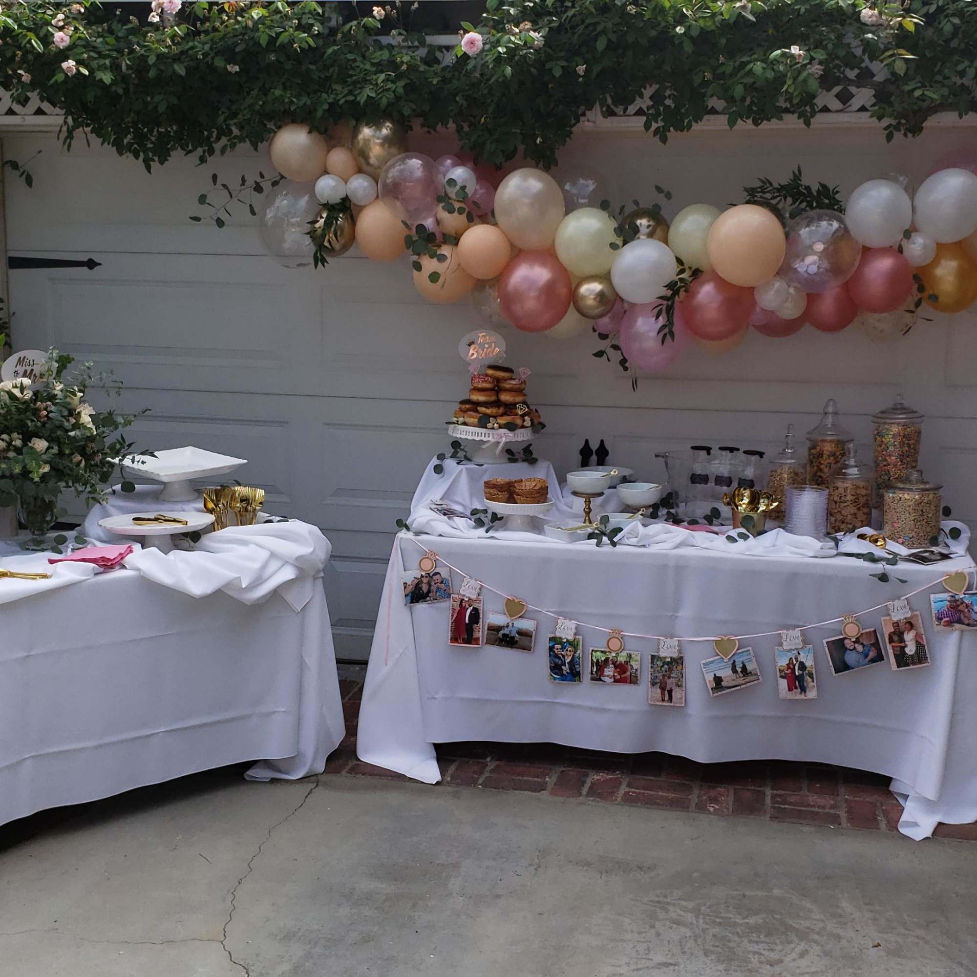 Balloon garland over two decorated tables with flowers and desserts
