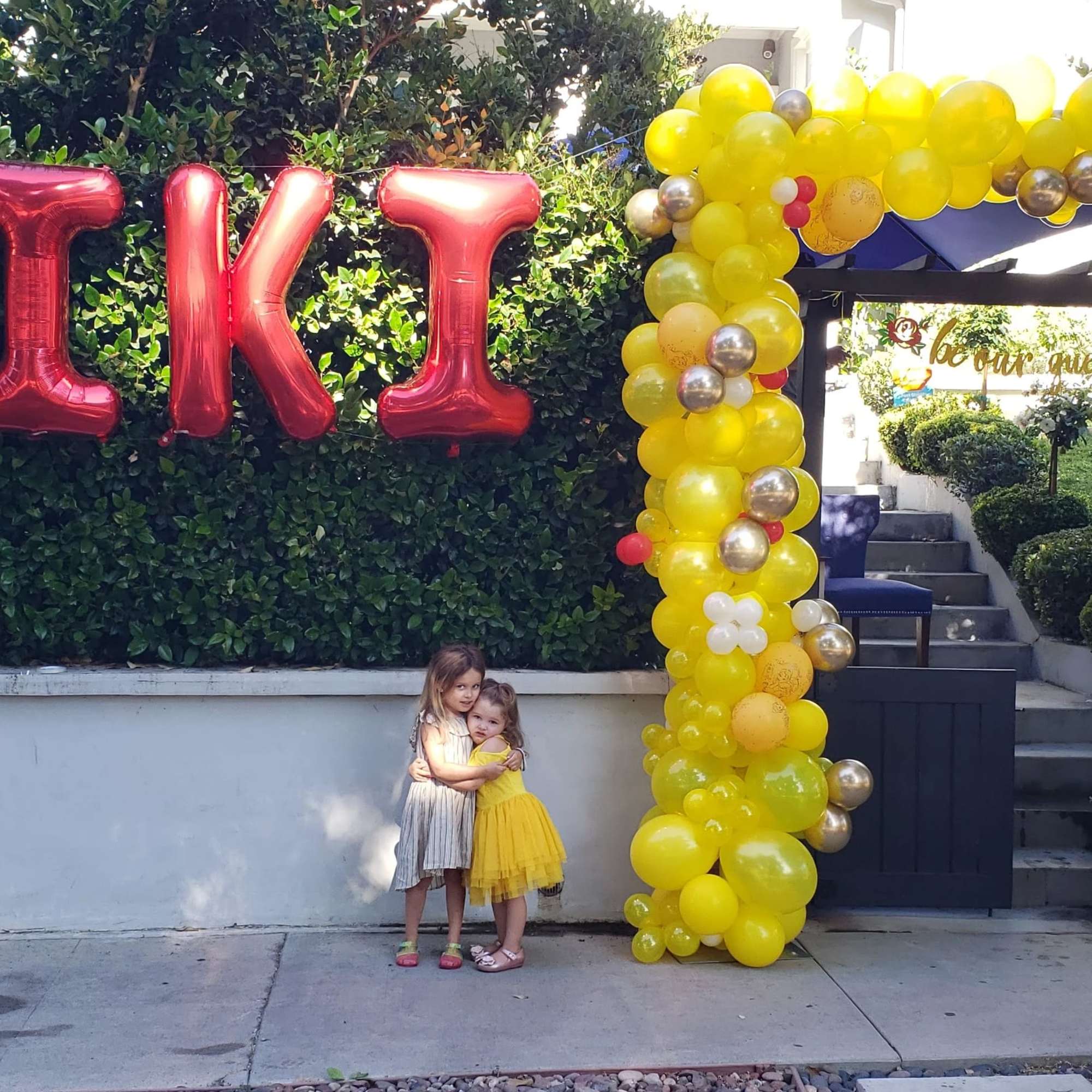 Yellow balloon arch with red "KIKI" balloons and princess balloons