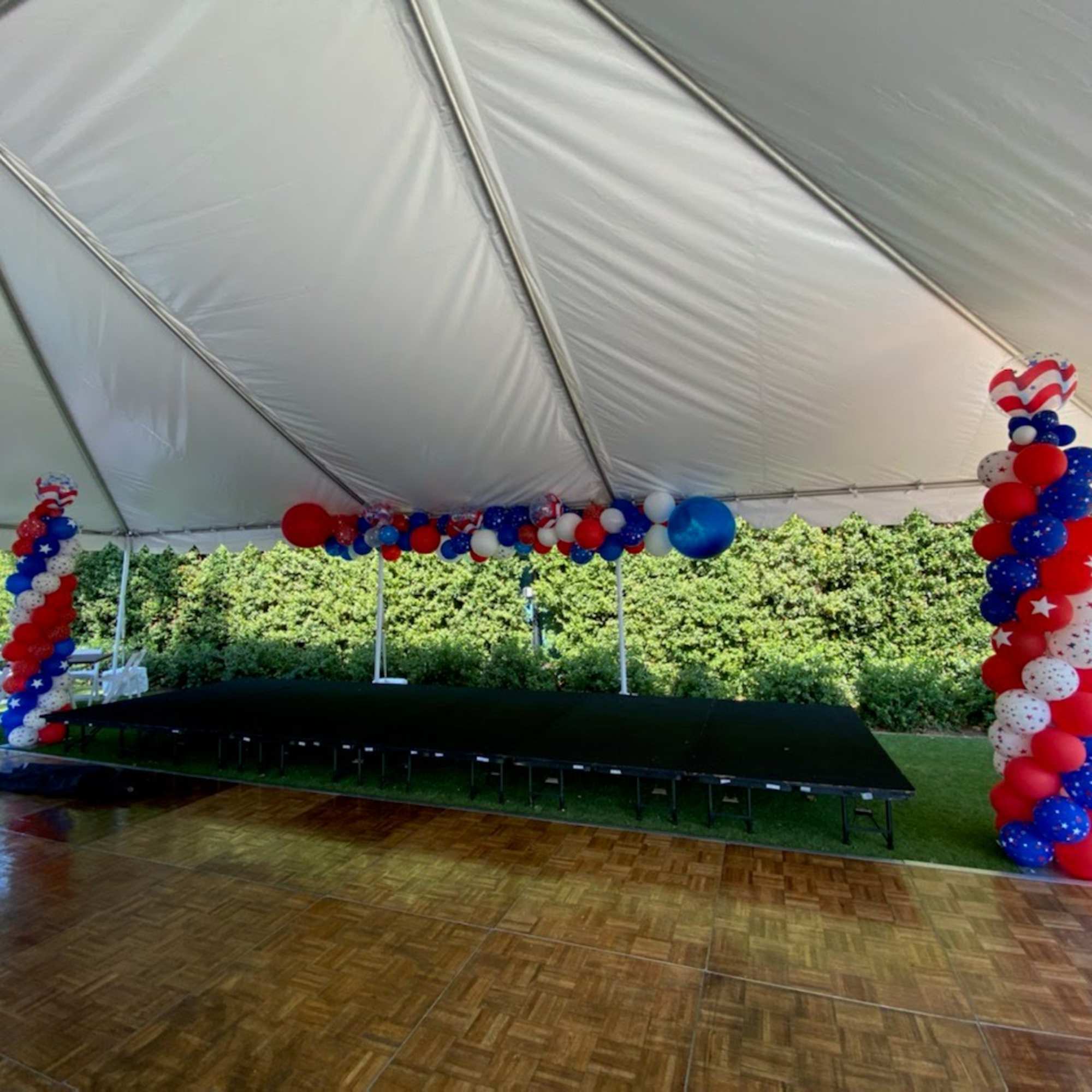 Red, white, and blue balloon columns and garlands inside a tented event space