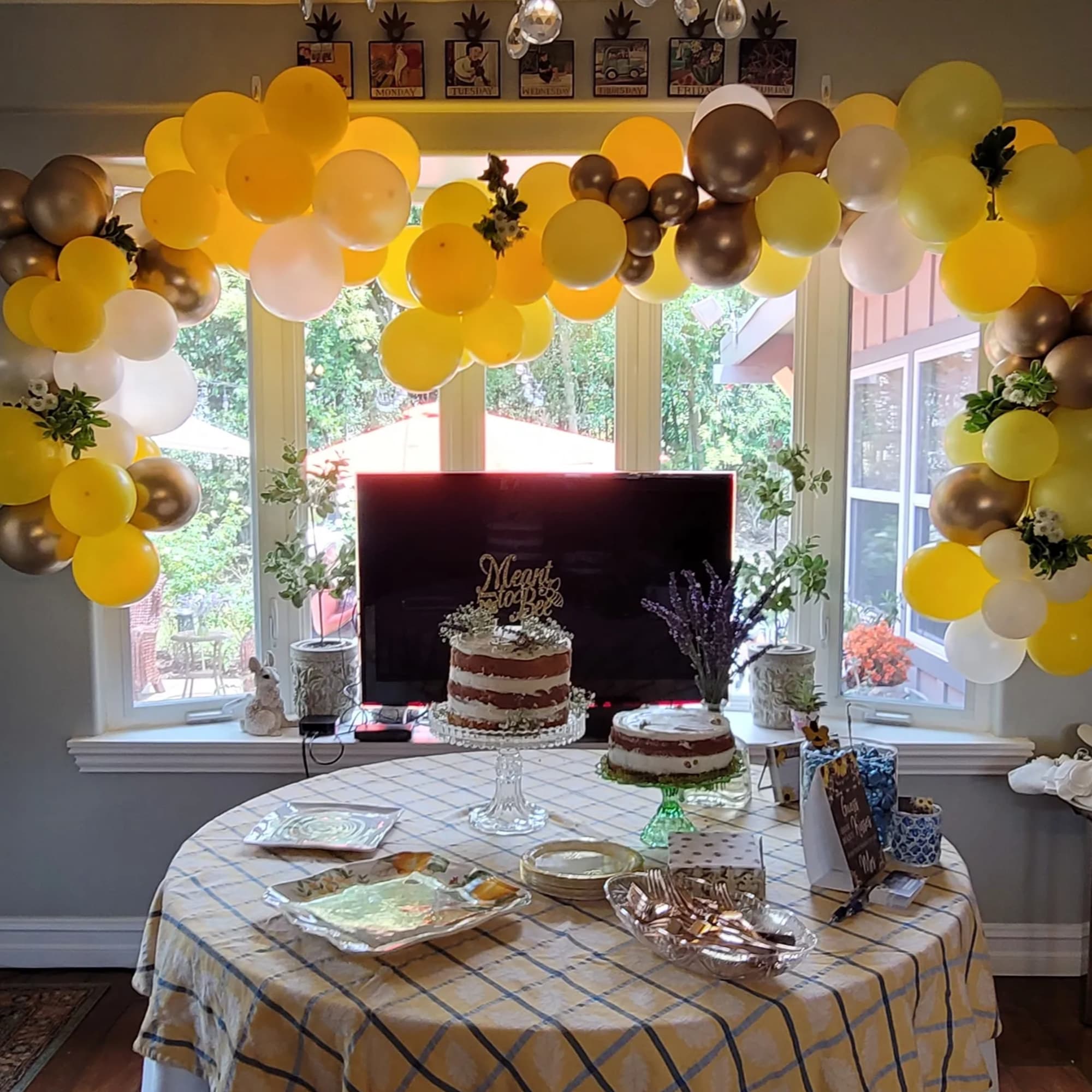 Yellow, white, and gold balloon garland over a dessert table with cakes