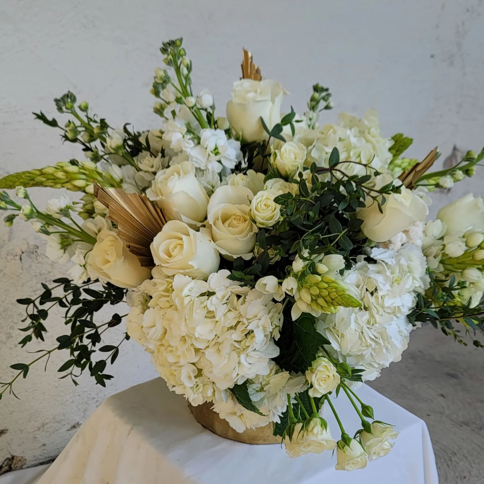 White rose and hydrangea arrangement in a gold vase