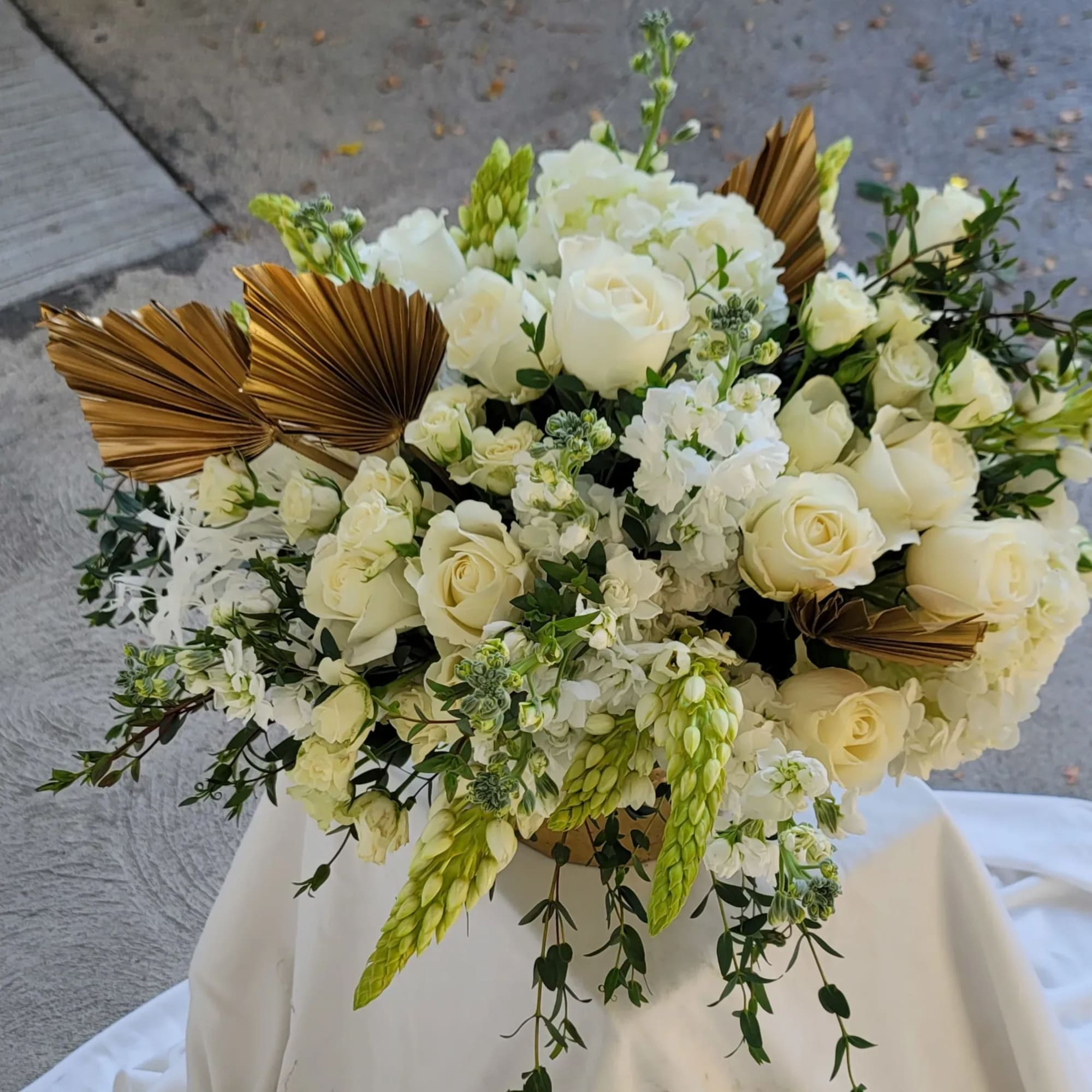 White rose and hydrangea arrangement with gold fan accents