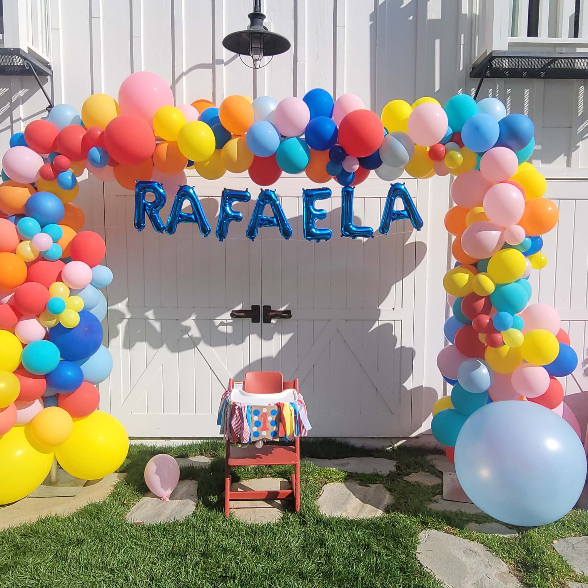 Colorful balloon arch with "RAFAELA" letters in front of white doors