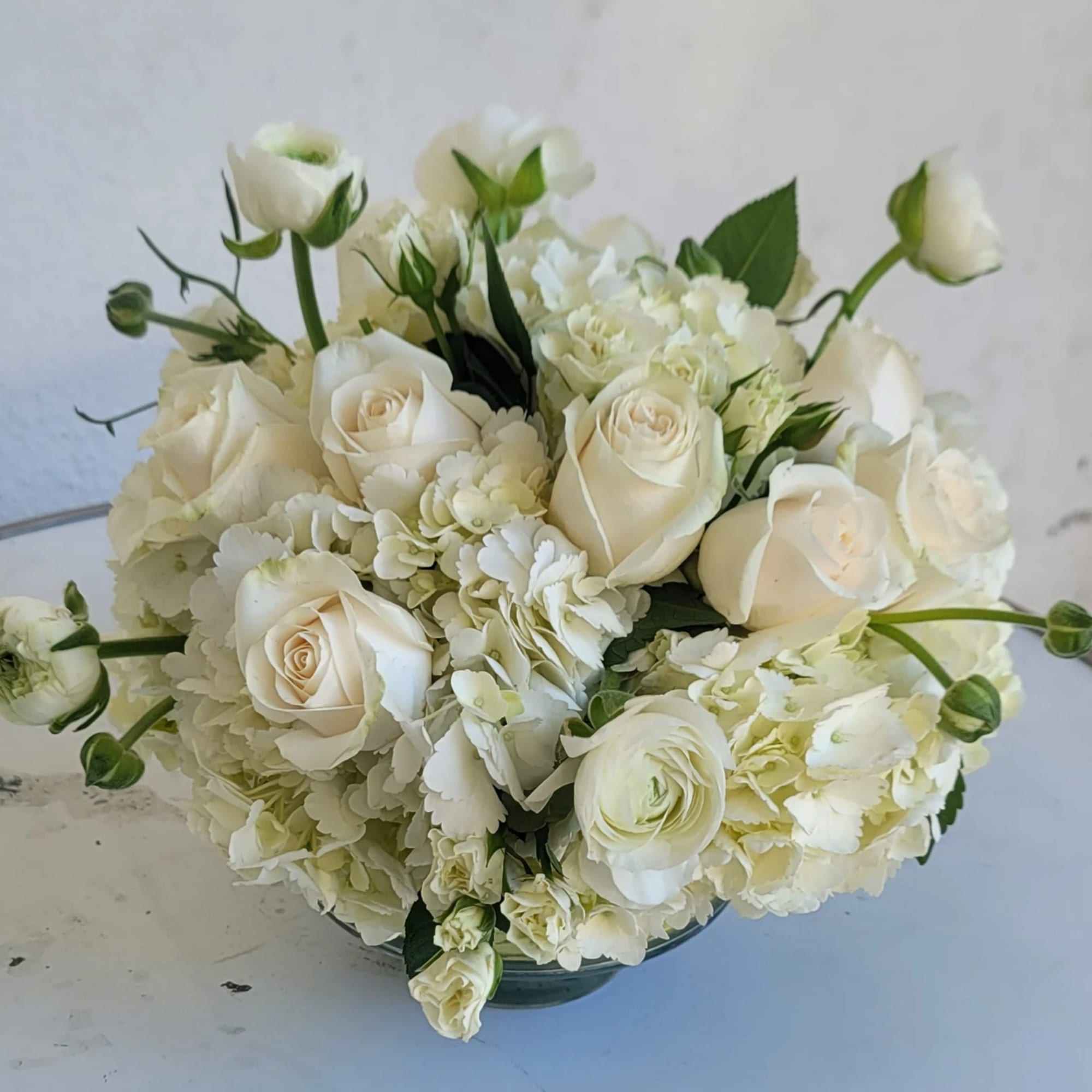 White roses and hydrangeas arranged in a low bowl vase