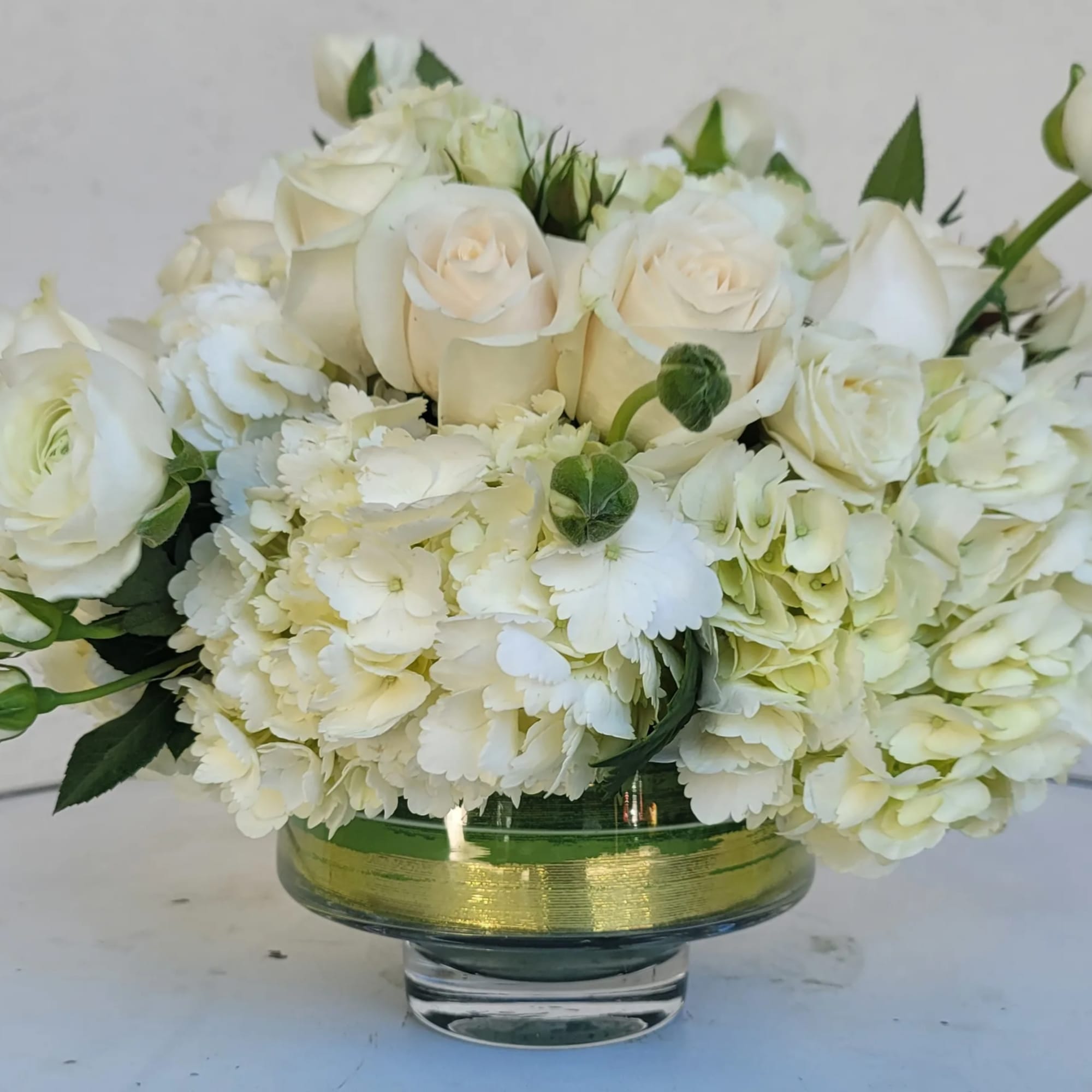 White roses and hydrangeas arranged in a glass vase