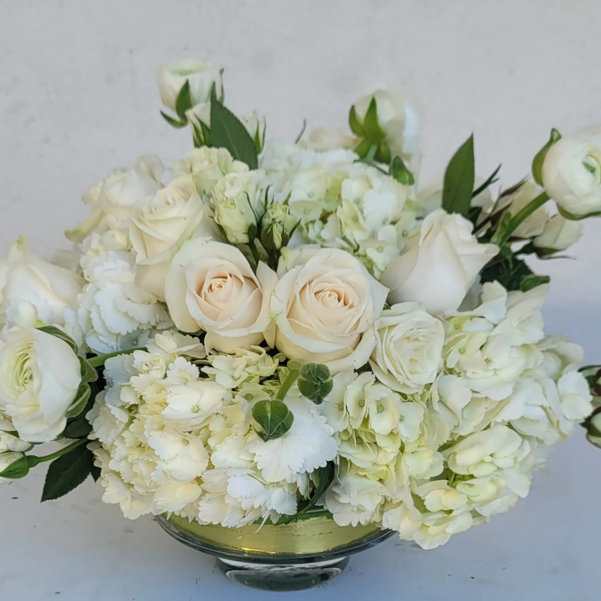 White roses and hydrangeas arranged in a low glass bowl