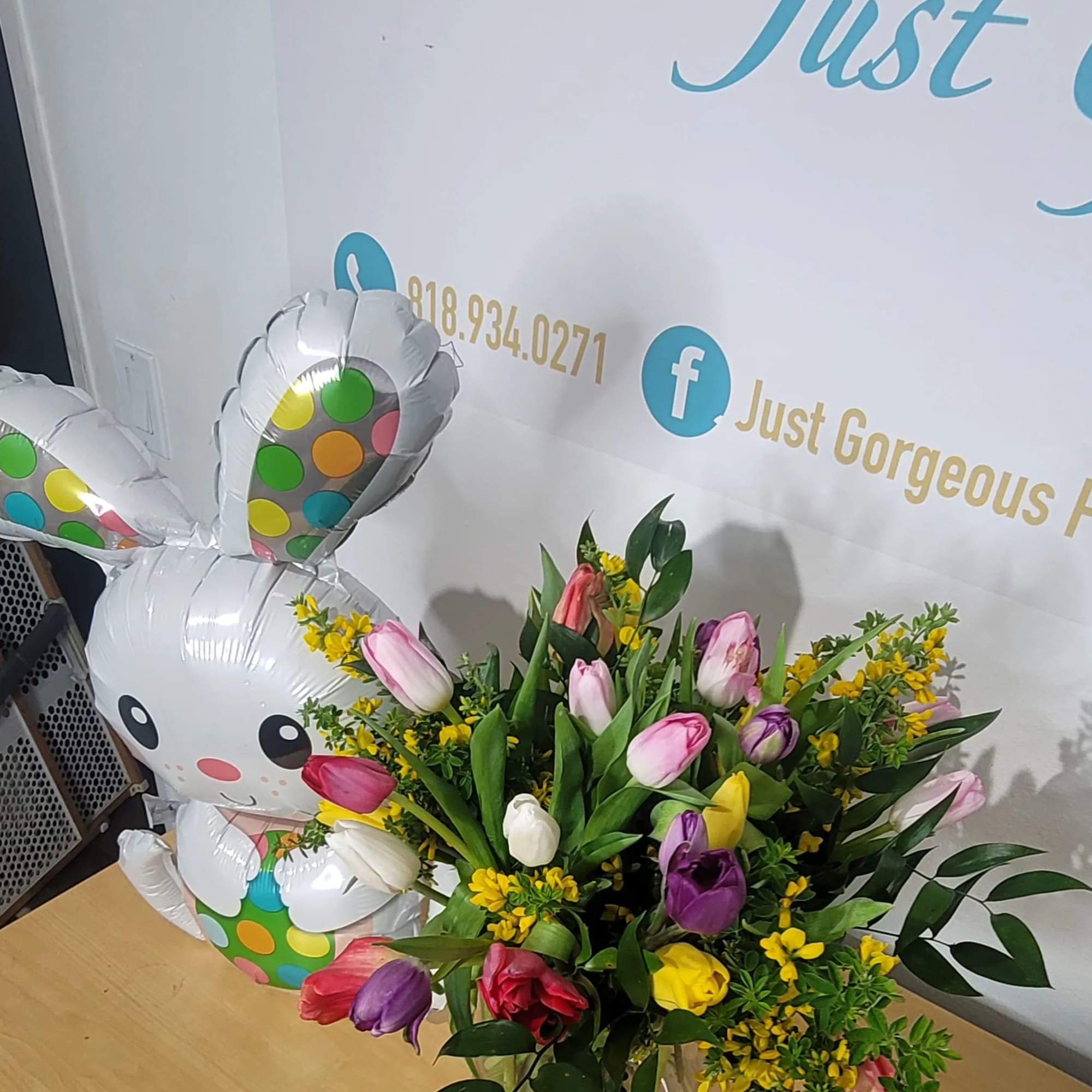 Bouquet of multicolored tulips in a clear glass vase beside a bunny balloon
