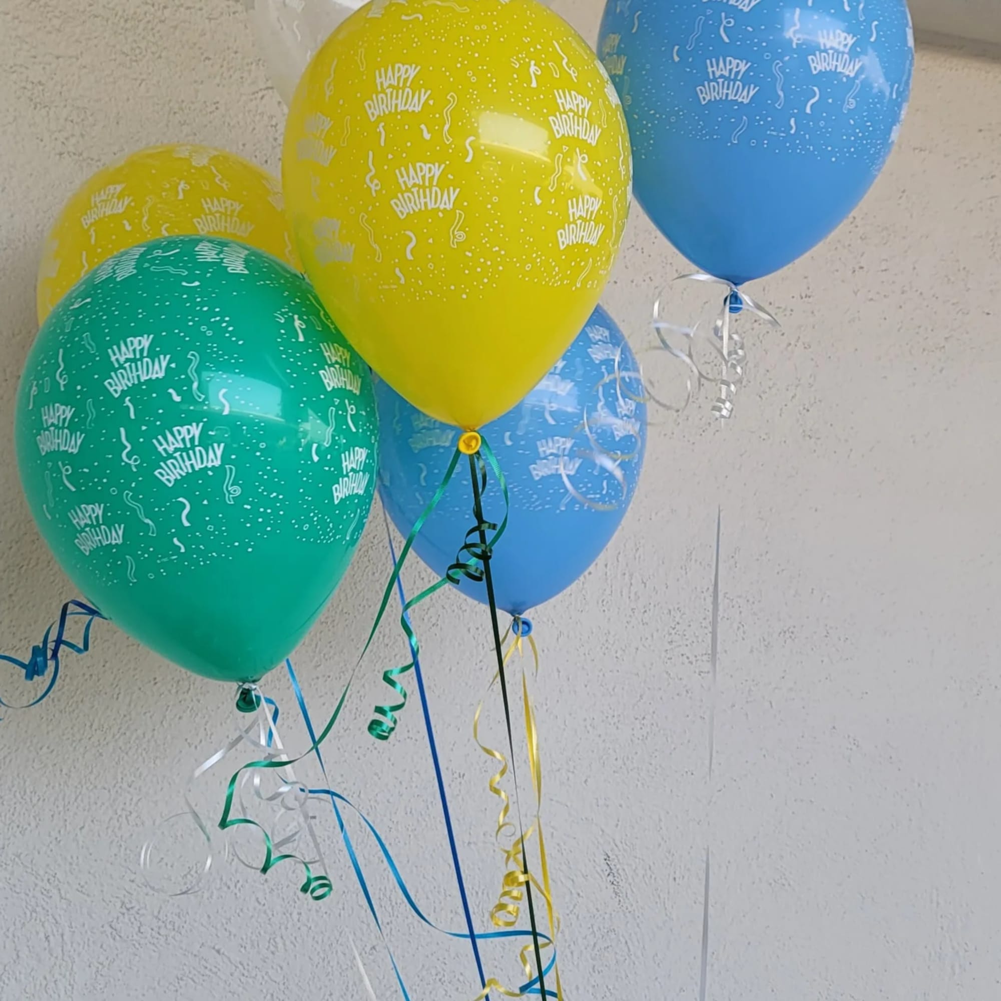 Cluster of colorful birthday balloons with curling ribbons
