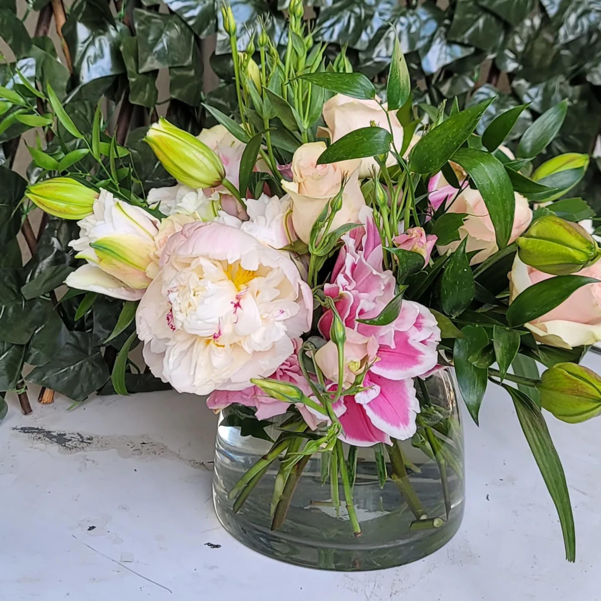 Pink and white flowers arranged in a clear glass vase